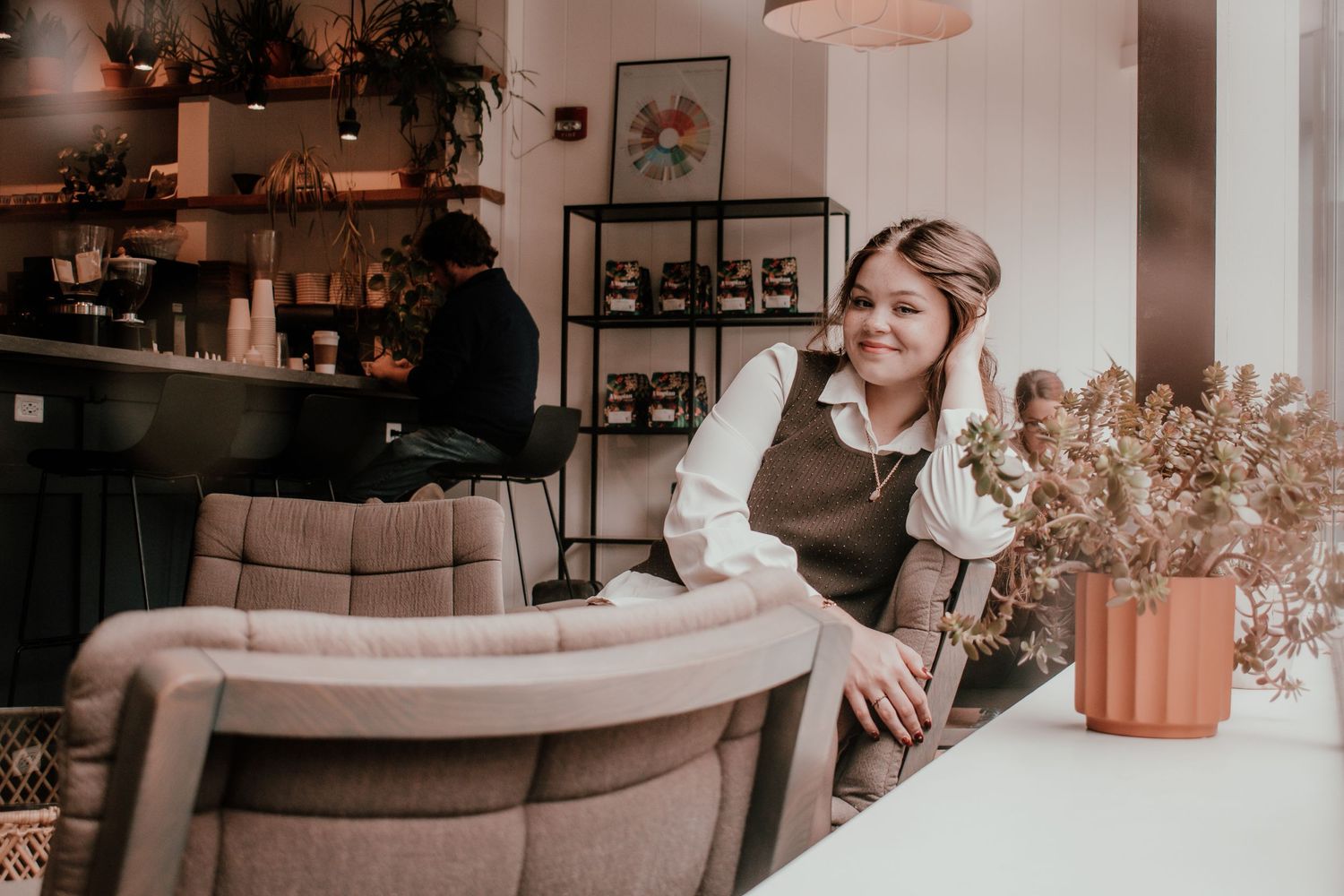 A cozy cafe interior with neutral tones, potted plants and modern furnishings creates a warm, inviting atmosphere.