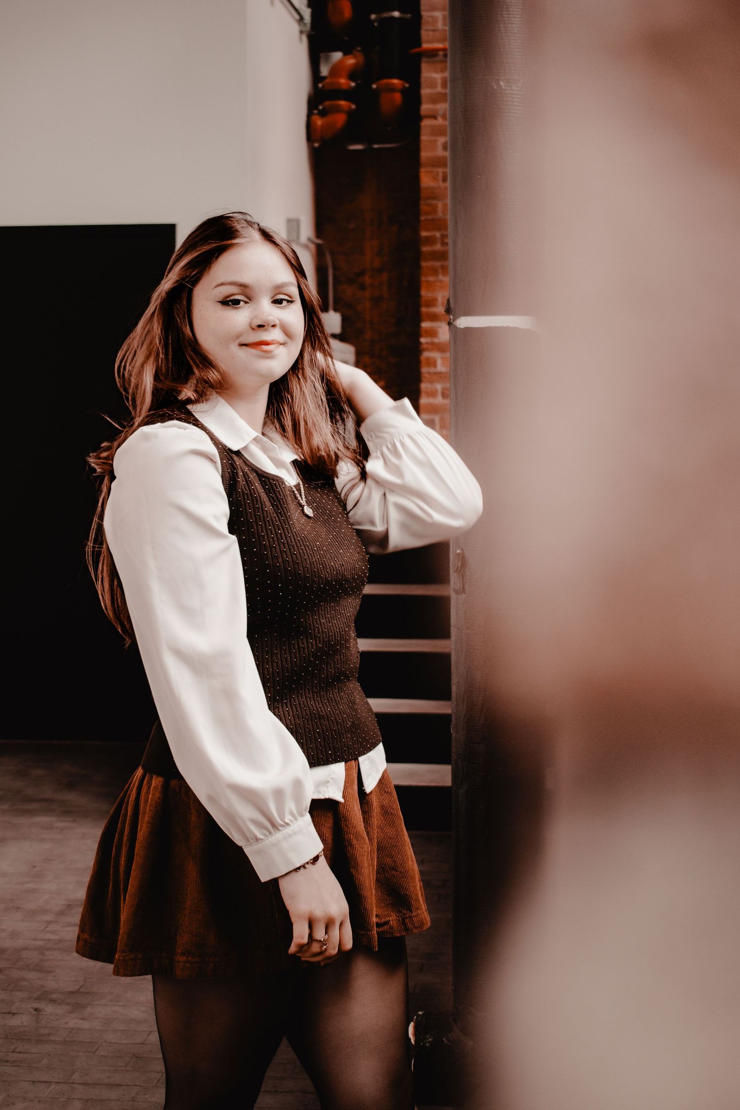 Vintage-inspired outfit featuring brown skirt and vest with white blouse in indoor setting.