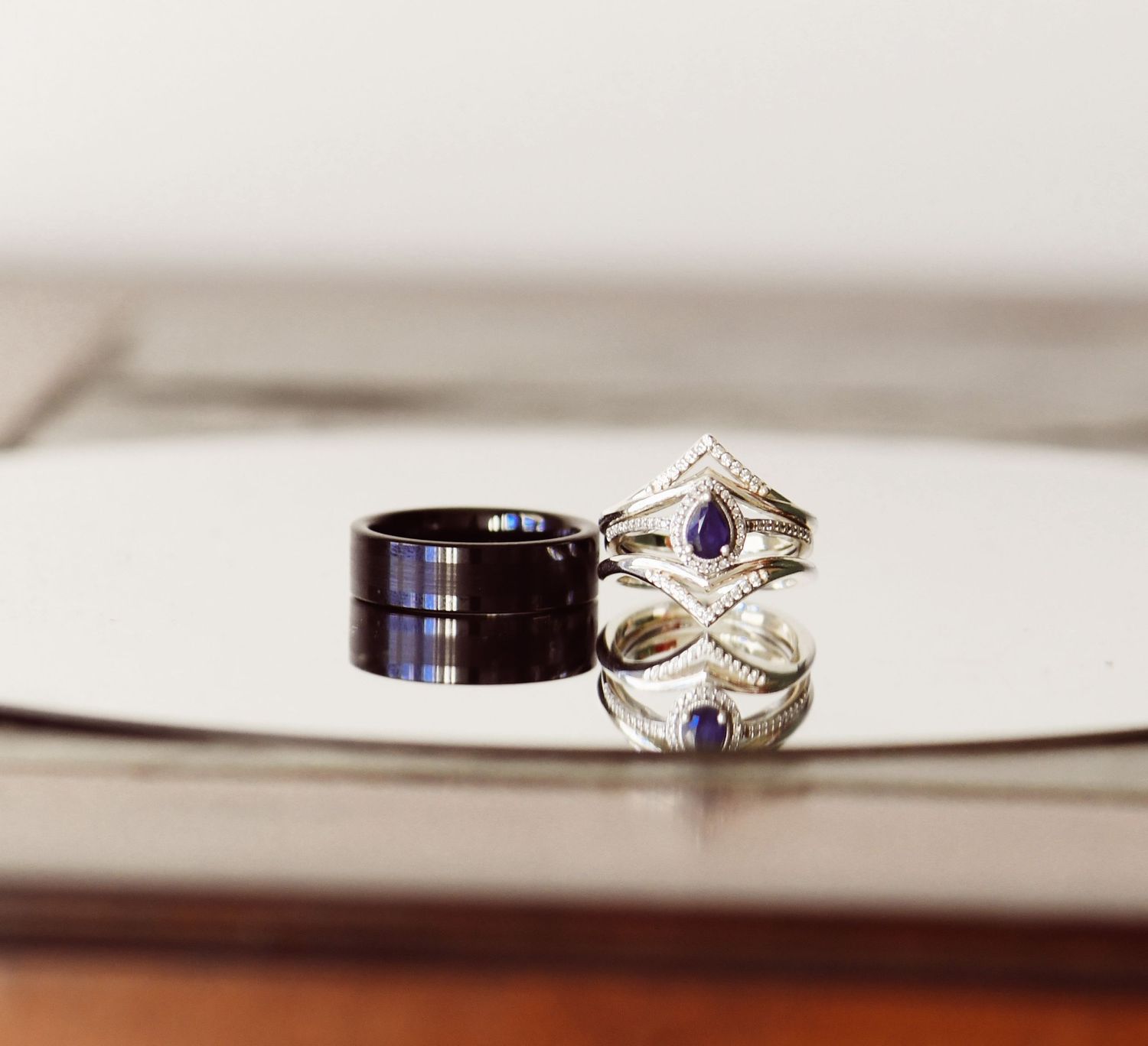 Wedding rings displayed on reflective surface showing elegant design details.