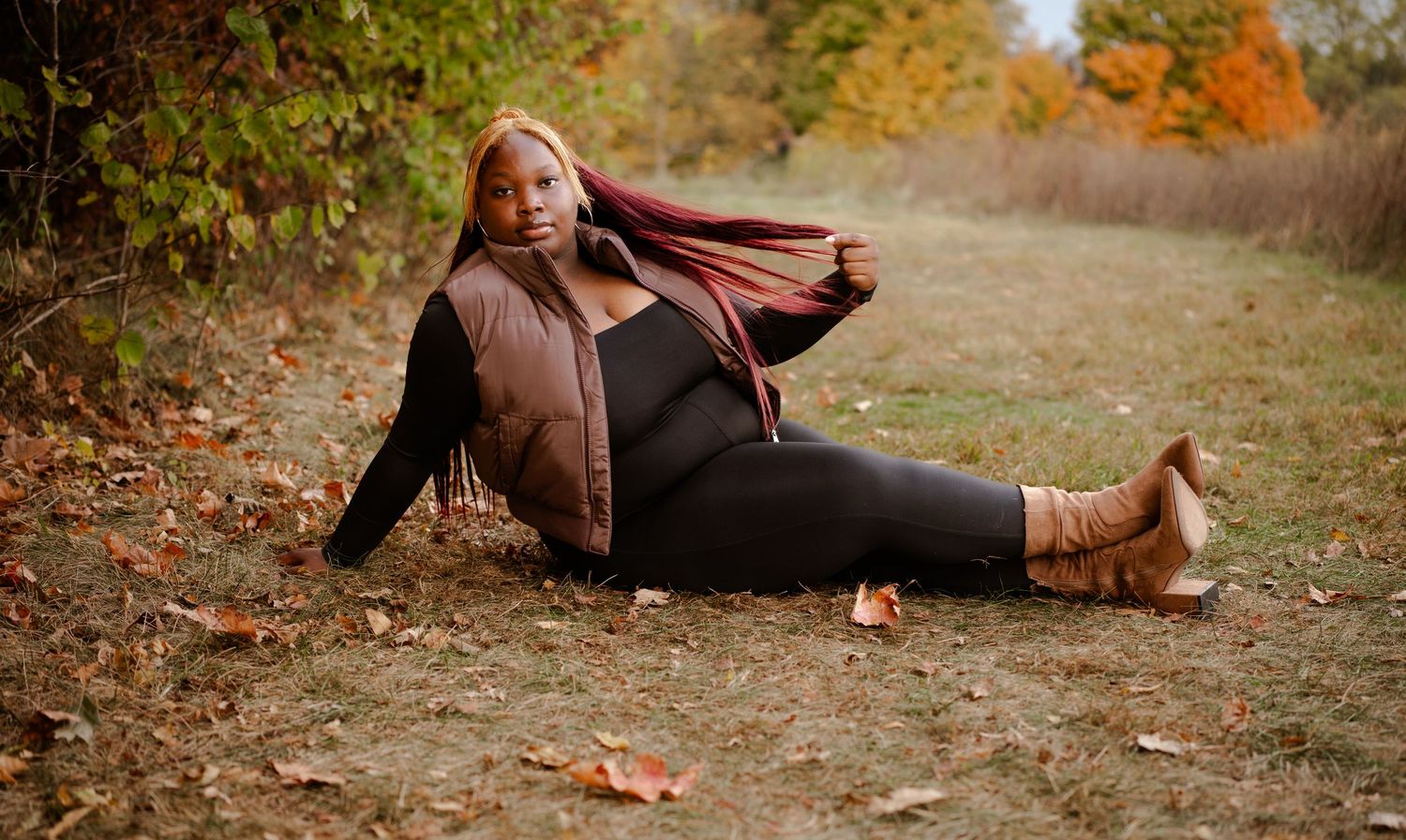 Autumn outdoor portrait in brown attire lying on fallen leaves.