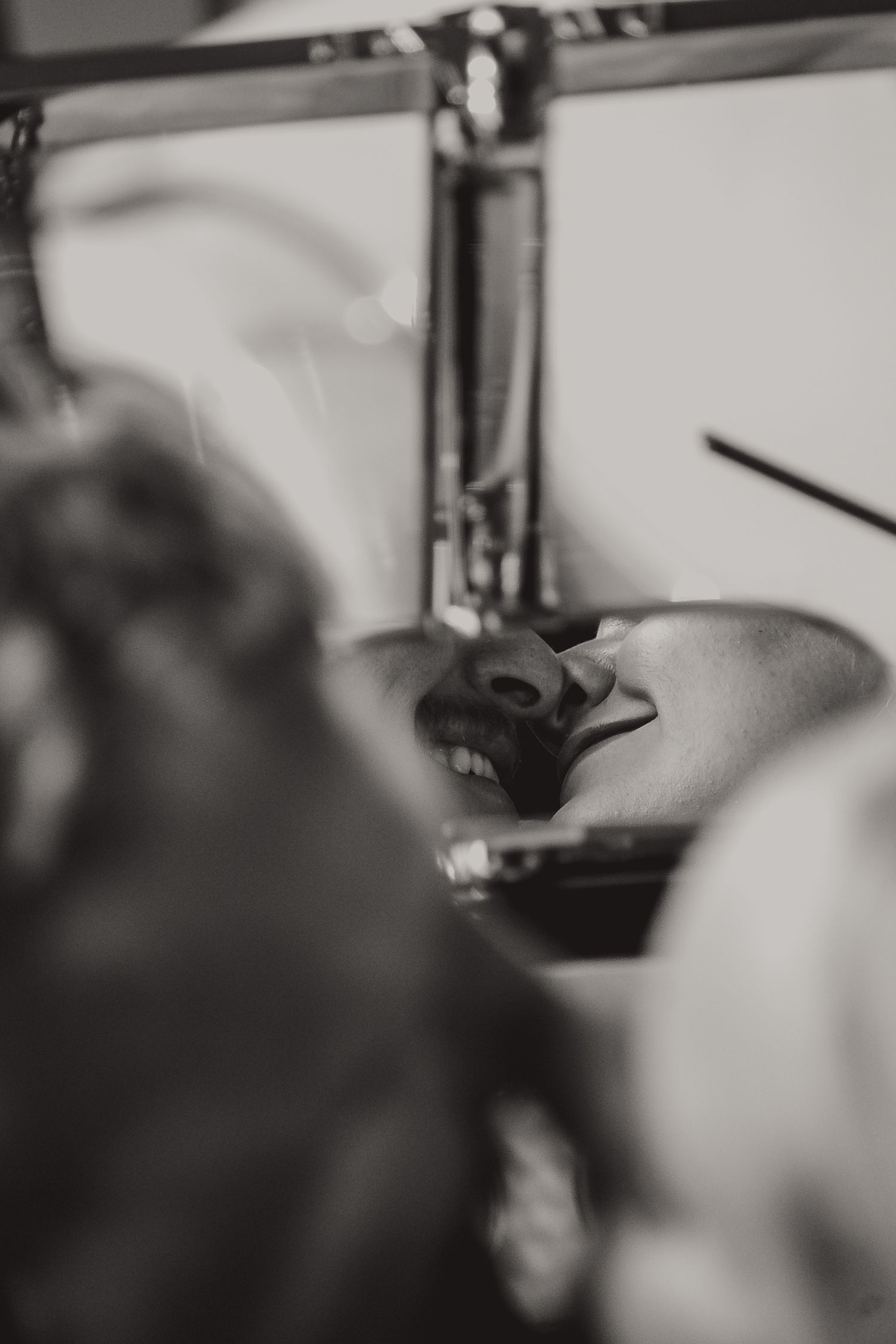 Black and white close-up photo of a person laughing with head tilted back, captured from an artistic angle.