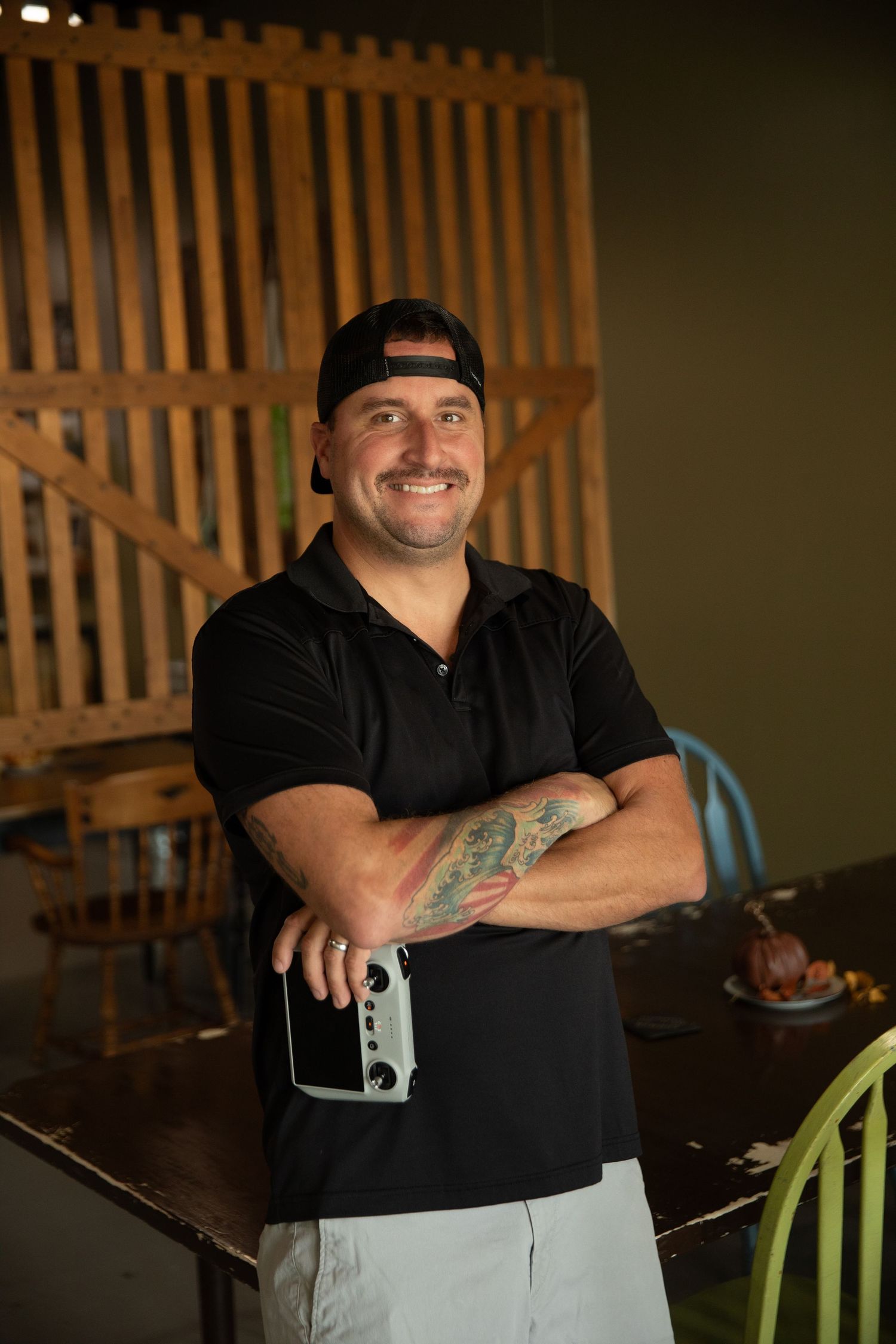 Professional studio photography portraits showing casual poses in black shirt against wooden slat background.