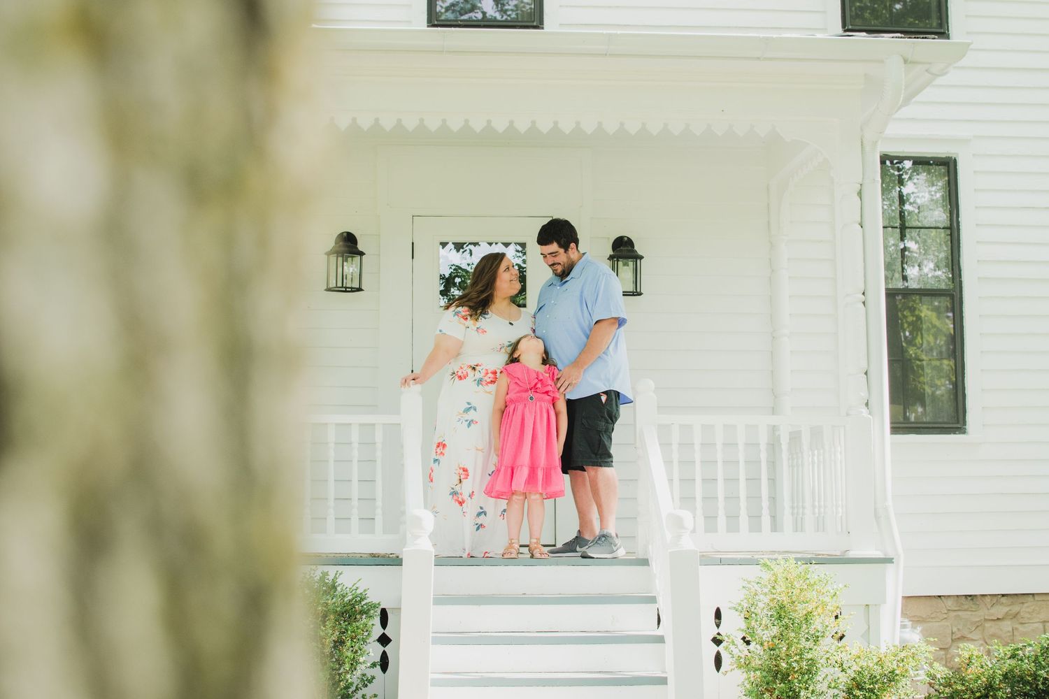 Family moment captured on a white porch of a classic American home.