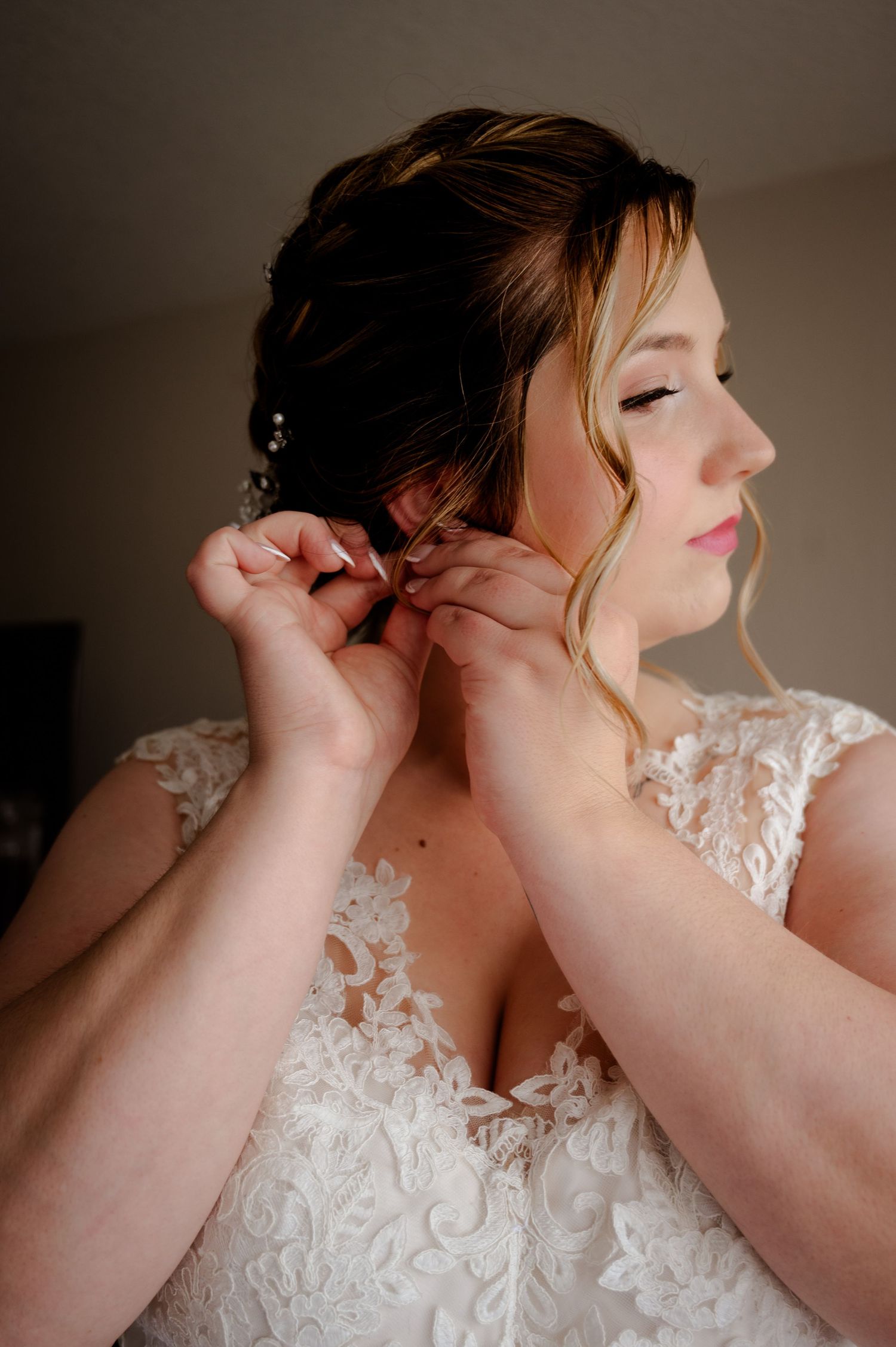 A series of photos show someone adjusting a delicate lace wedding dress with soft lighting in a romantic style setting.