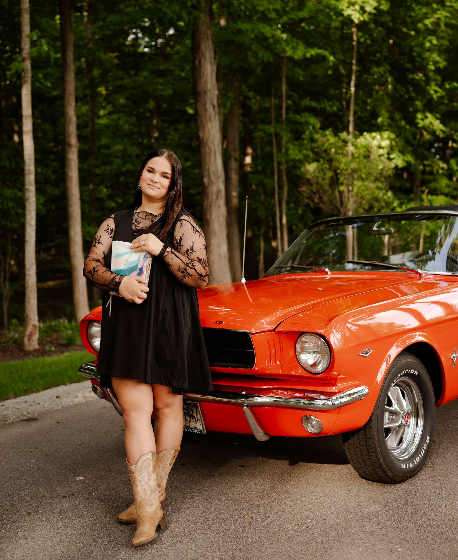 Bright orange vintage car photographed in a lush forest setting during an outdoor photoshoot session.