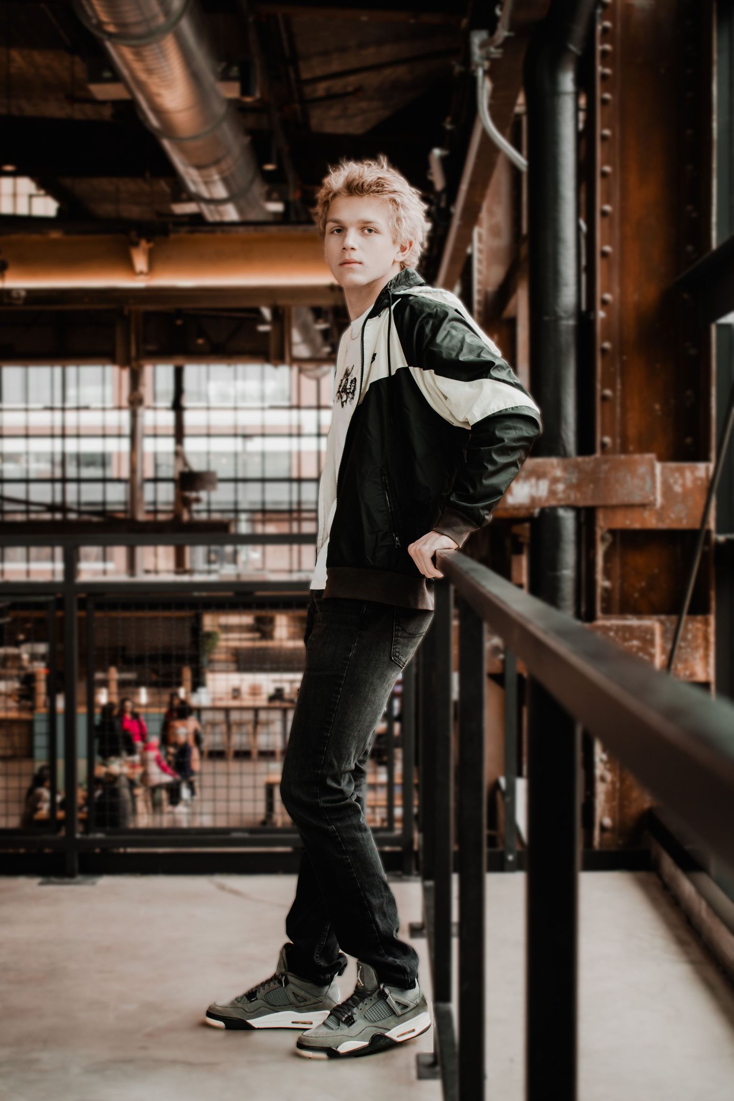 Urban fashion portrait showing sporty black and white jacket with sneakers in industrial setting.