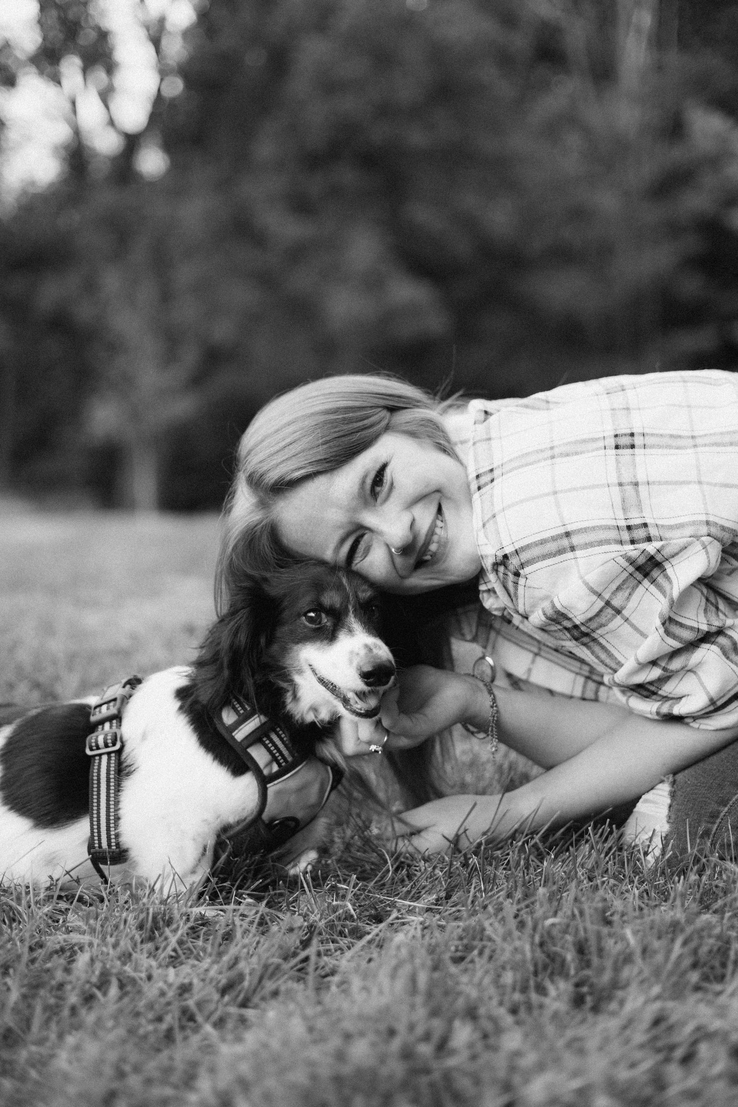 Black and white photo of someone lying in grass with a dog showing tender companionship.