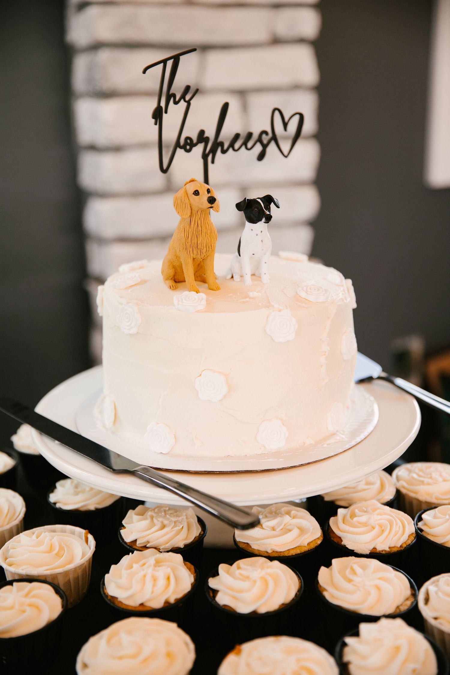 Wedding cake with peach frosting and cupcakes decorated with a golden dog cake topper.