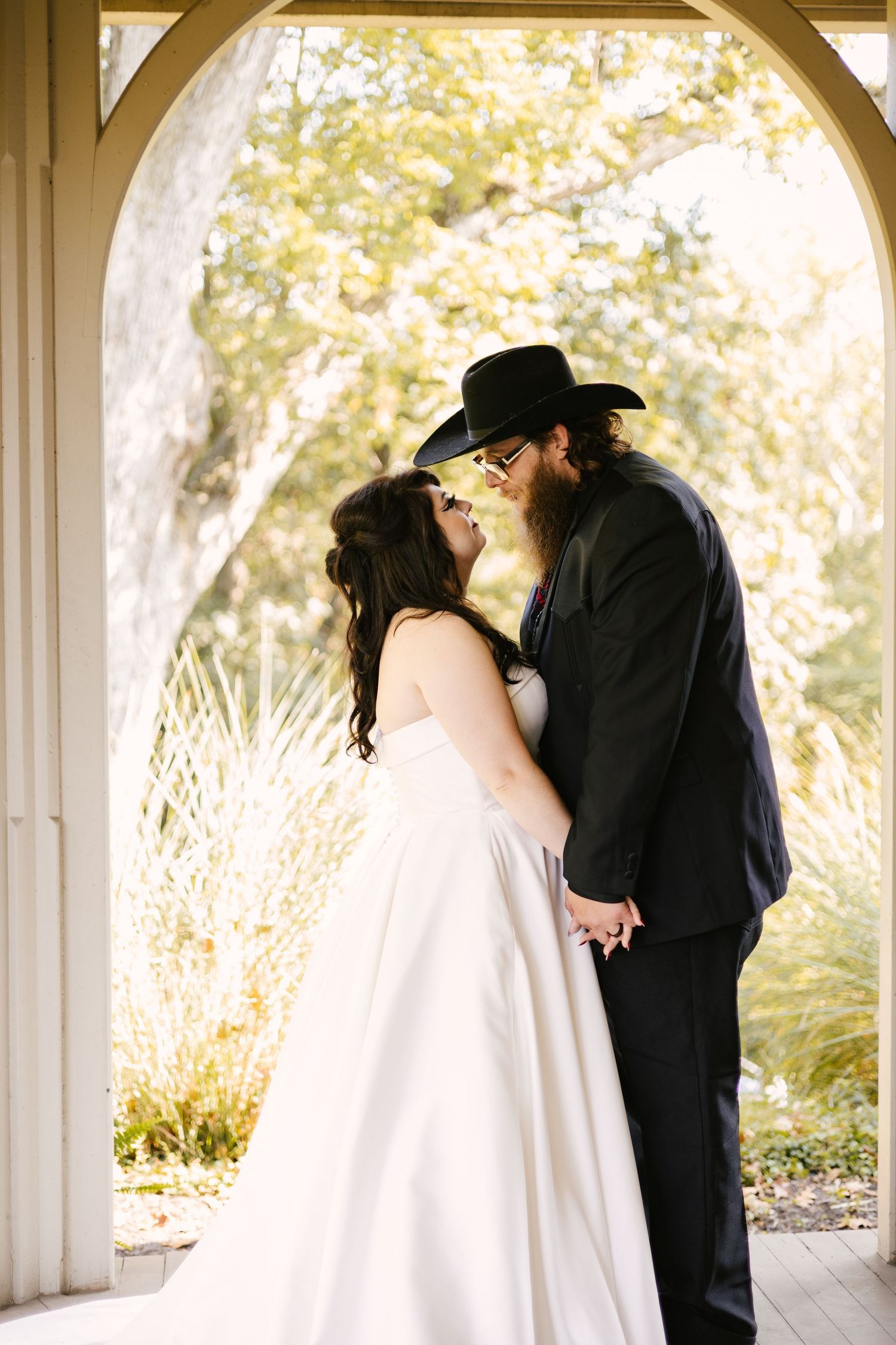 A series of romantic wedding photos showing a couple sharing intimate moments under white archways in natural light.
