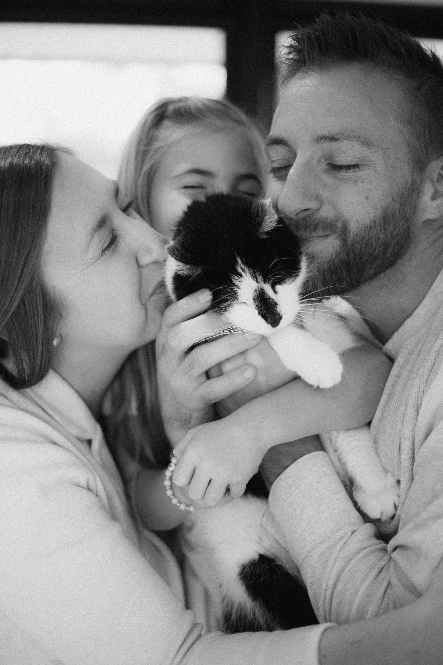 A black and white cat being cuddled and loved by its family in a tender moment.