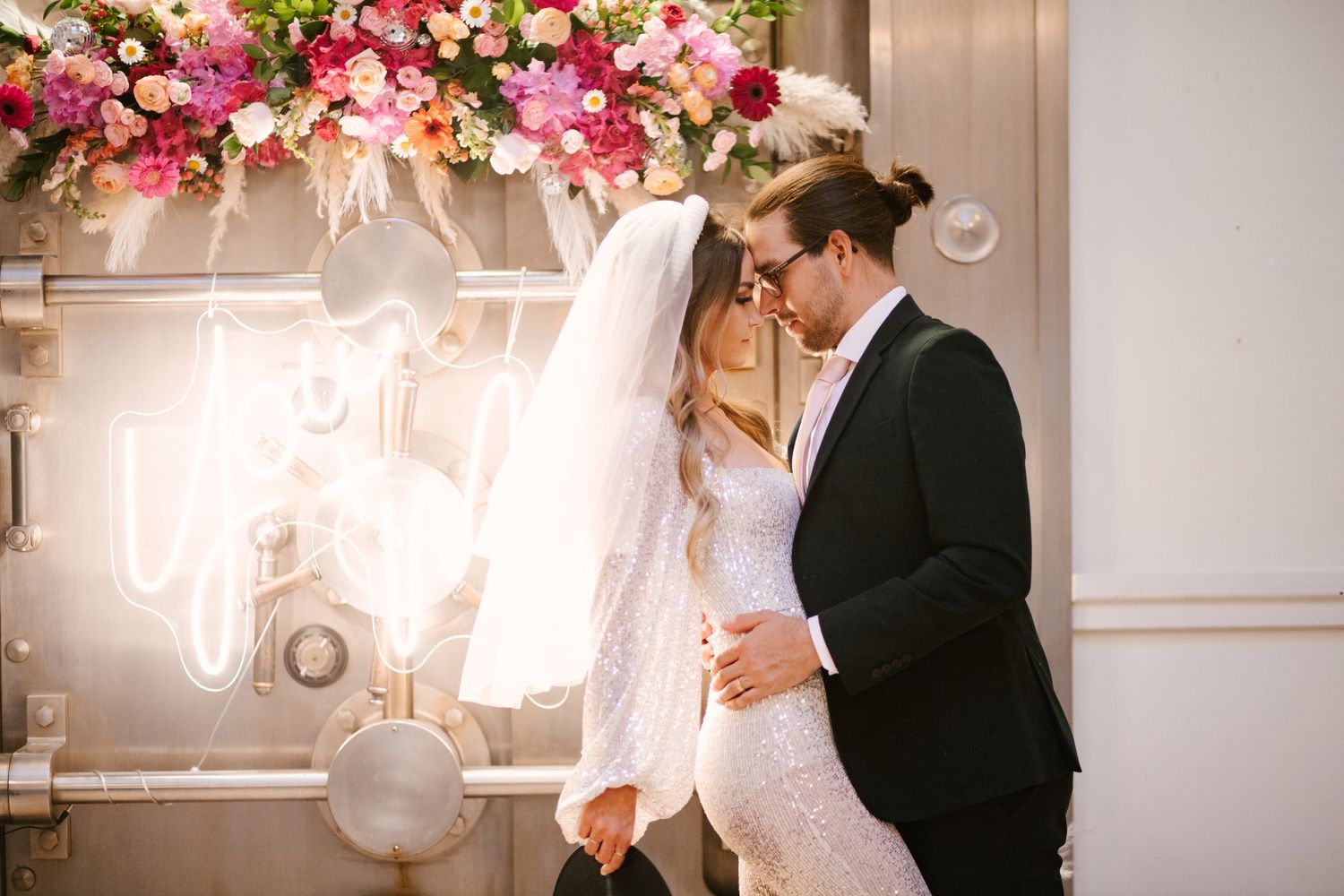 Wedding reception venue decorated with pink floral arrangements and glowing lights.