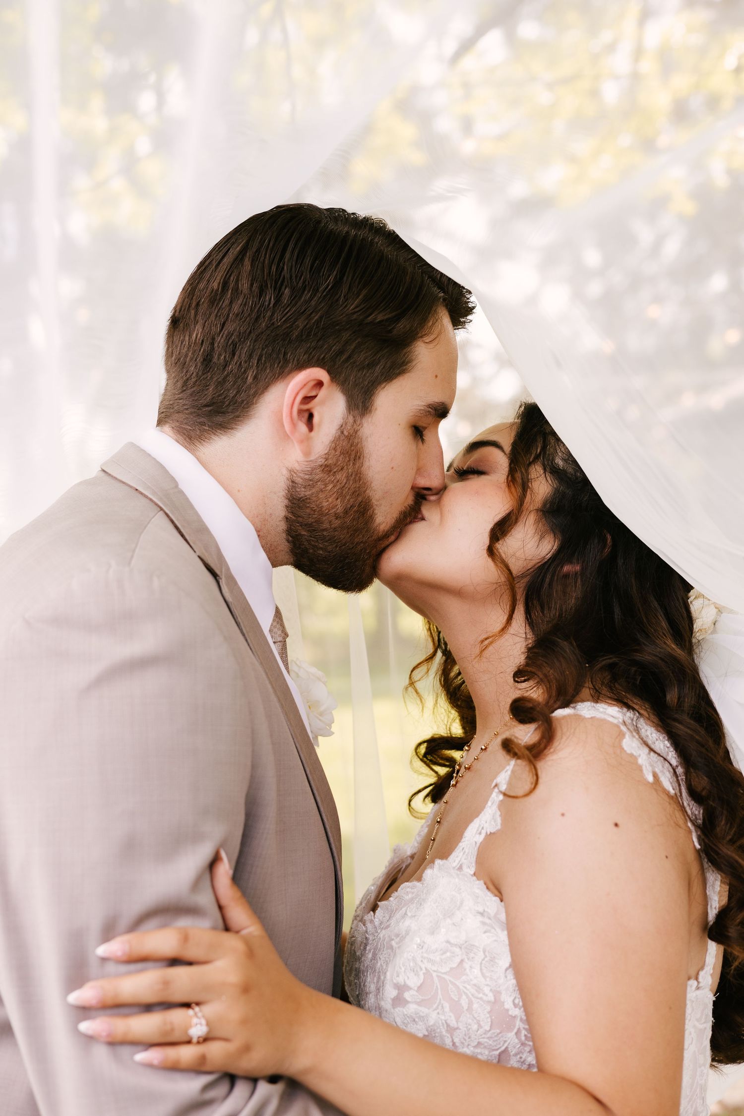 Tender wedding moment captured in soft natural light with delicate lace details.