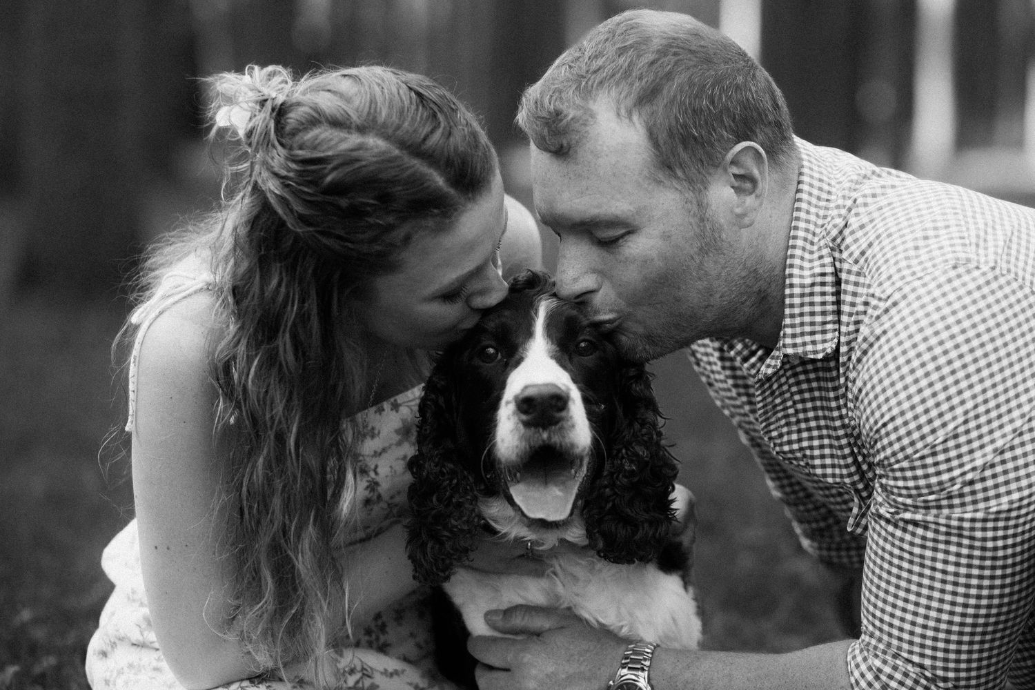 A couple embraces their dog while sharing affectionate moments in black and white portraits.