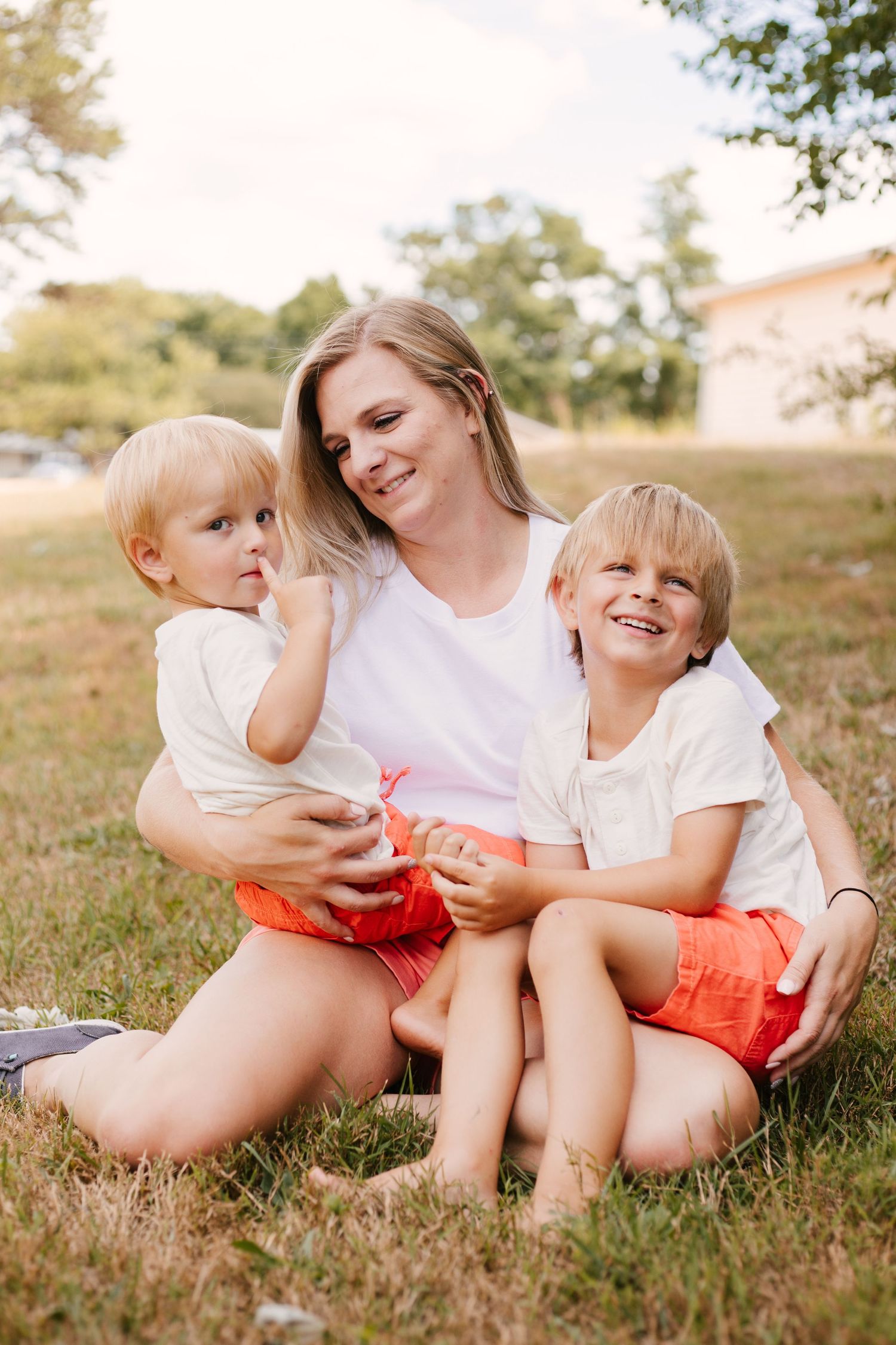 A tender family moment captured outdoors with coordinated white and coral clothing.