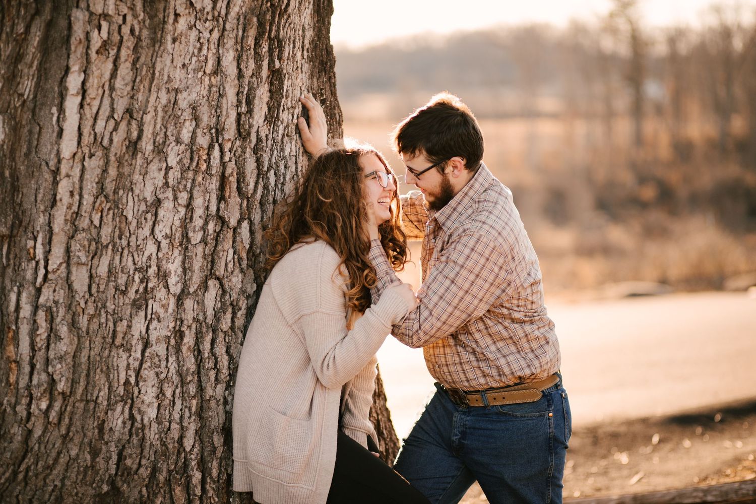 A romantic outdoor photoshoot at sunset with soft golden lighting filtering through trees.