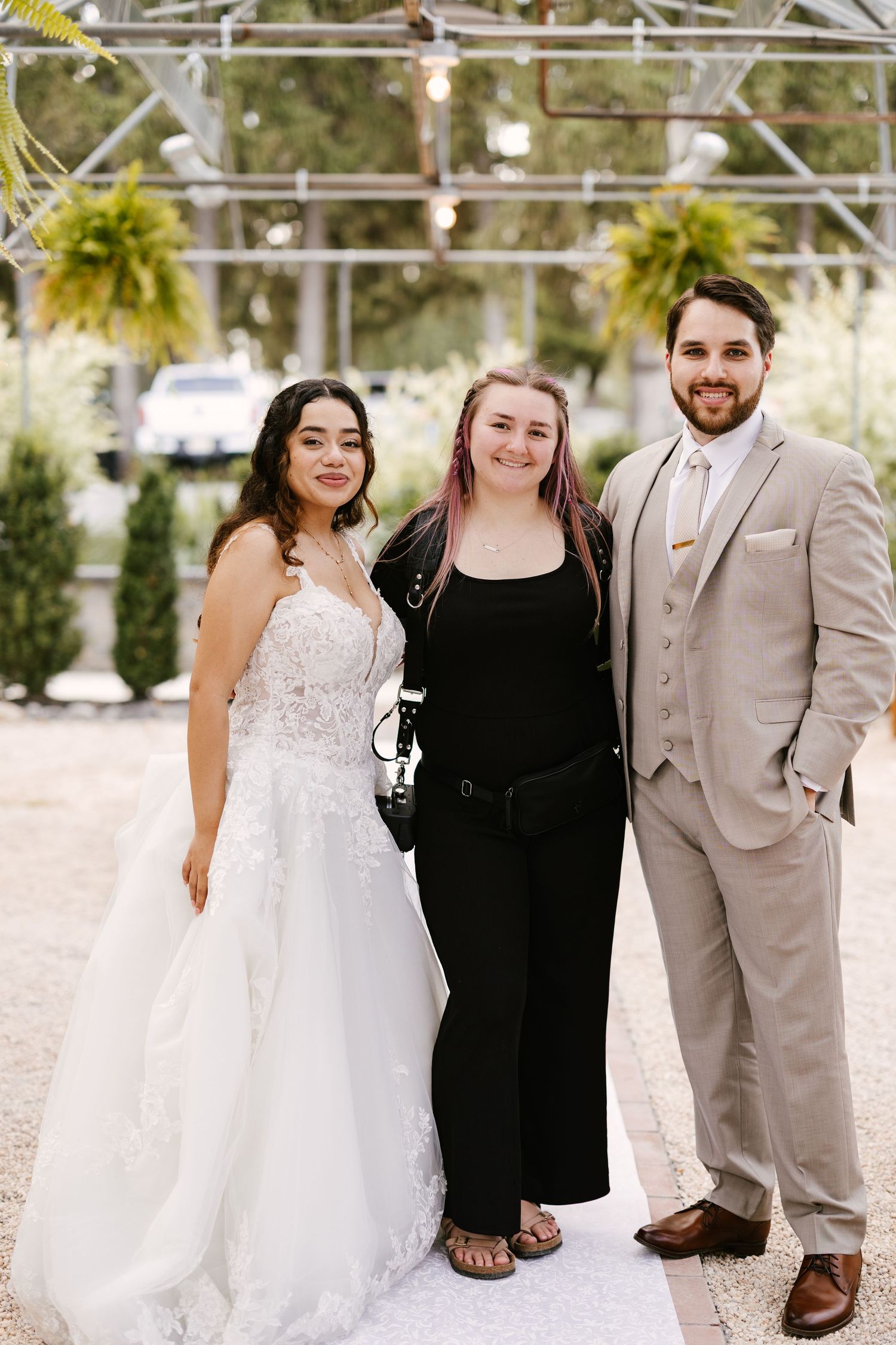Wedding party members pose together in formal attire against an outdoor backdrop.