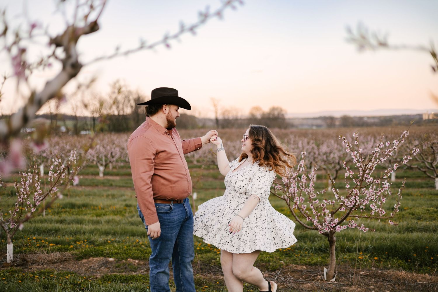 Romantic couple embracing among blooming fruit trees in spring orchard.