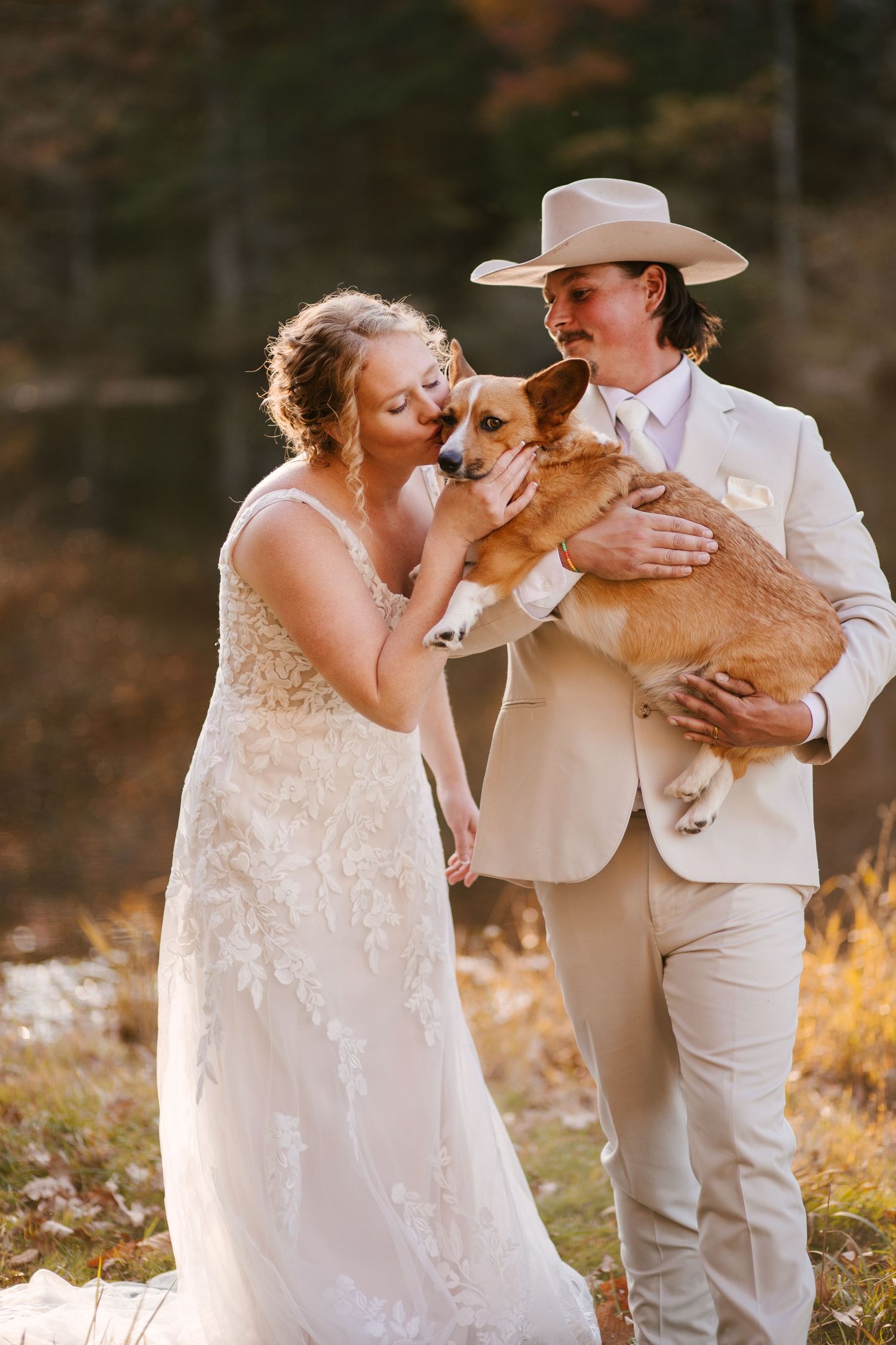 Wedding couple shares special moment with their golden retriever during outdoor portraits.