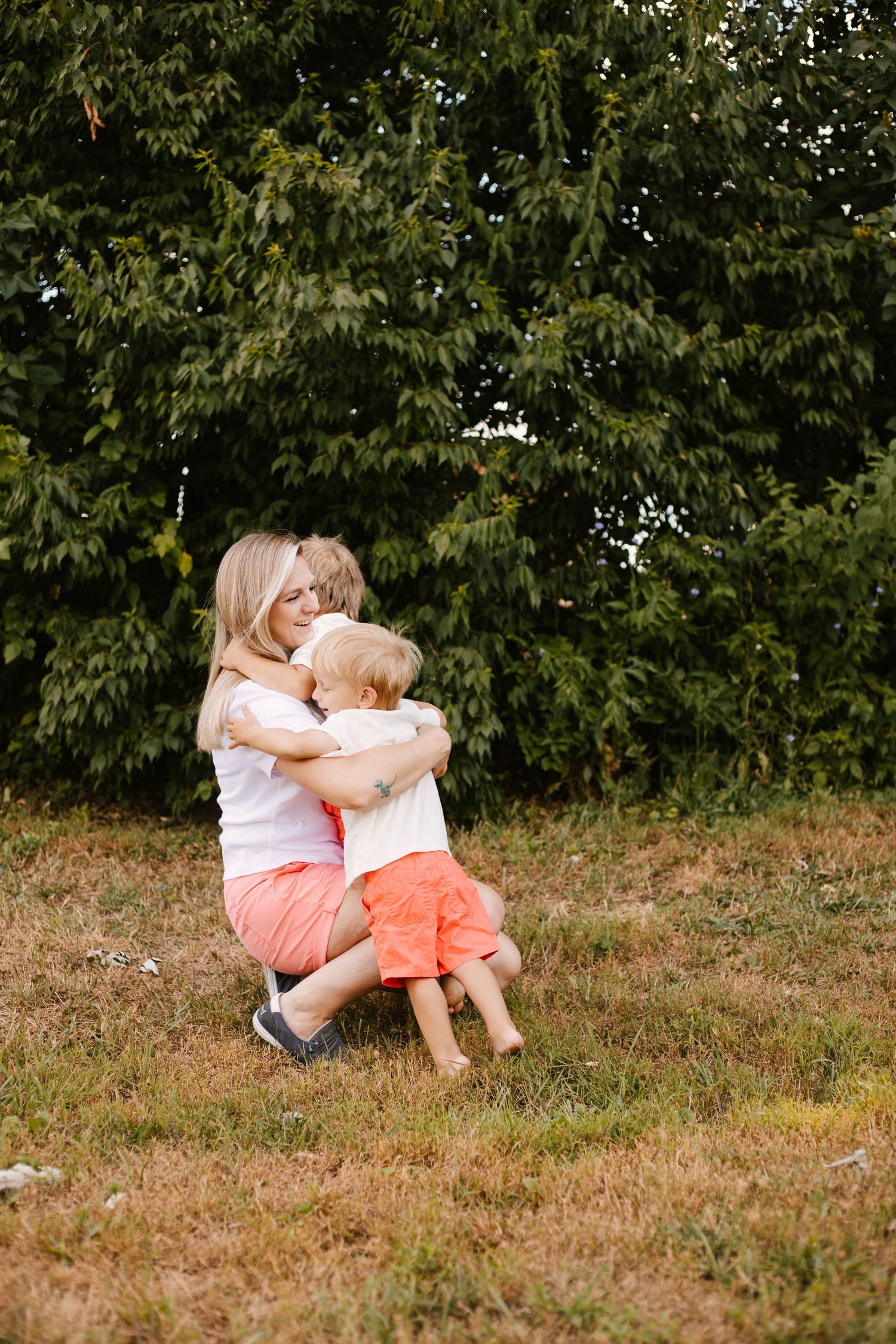 Family members in matching outfits share playful moments on grassy ground during sunset.