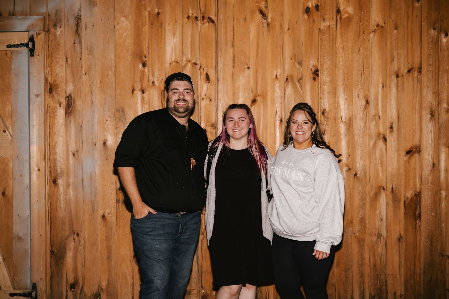 Casual group photo against wooden paneled wall at event venue.