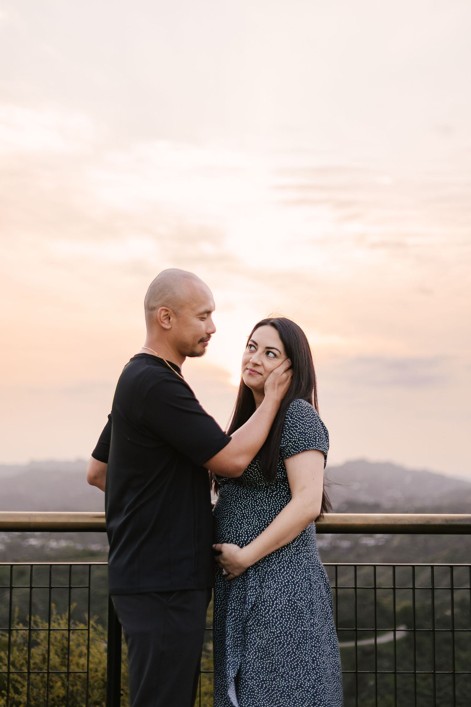 Couple embraces tenderly during sunset against a scenic mountain backdrop.