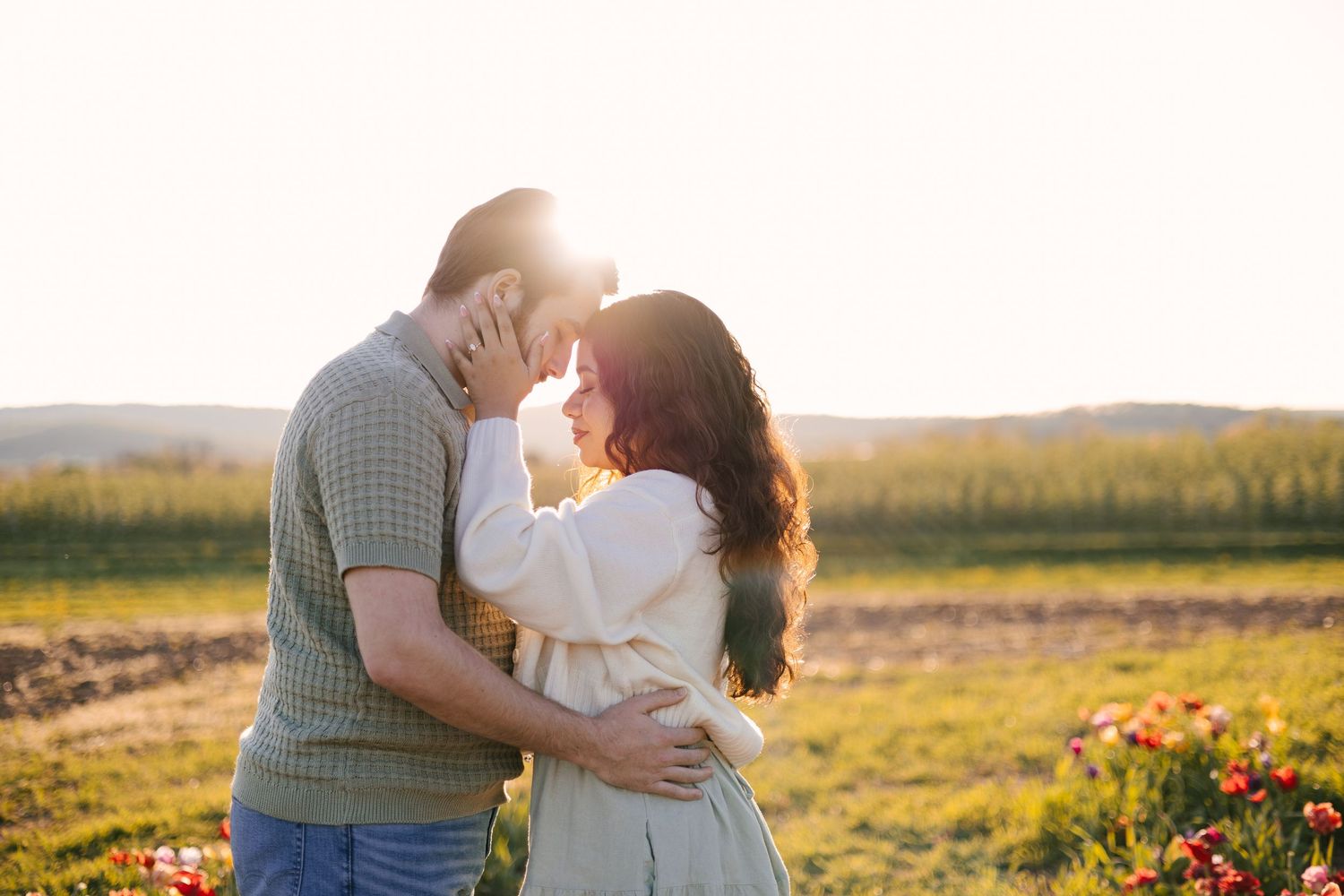 Romantic sunset engagement photoshoot in a golden field with wildflowers.