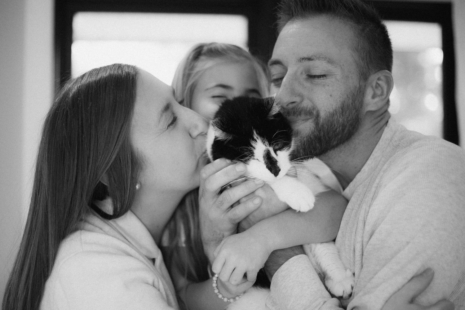 A romantic couple shares tender moments with their dog in a series of black and white photographs.