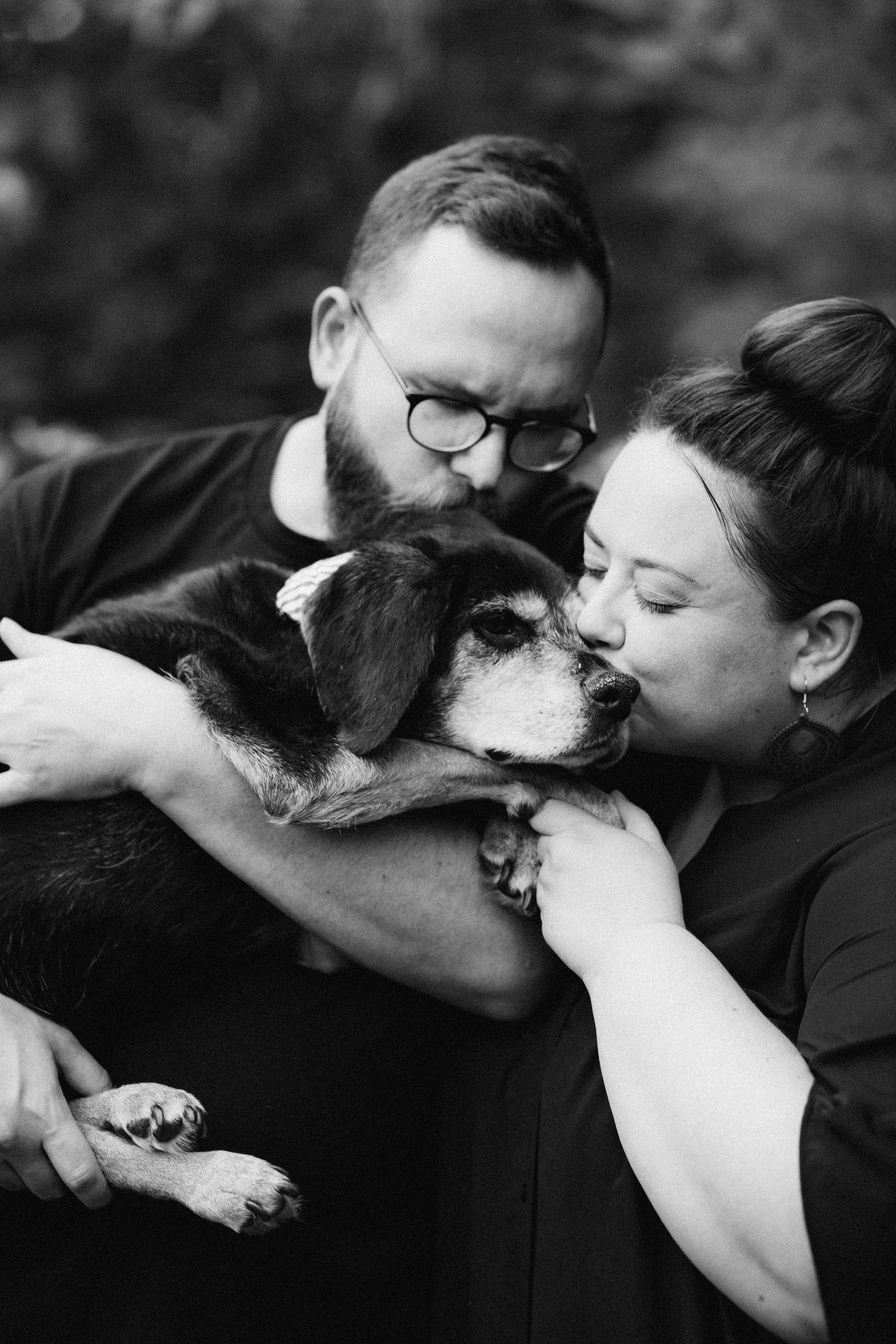 A sweet moment of affection between a dog and its loving owners in black and white.