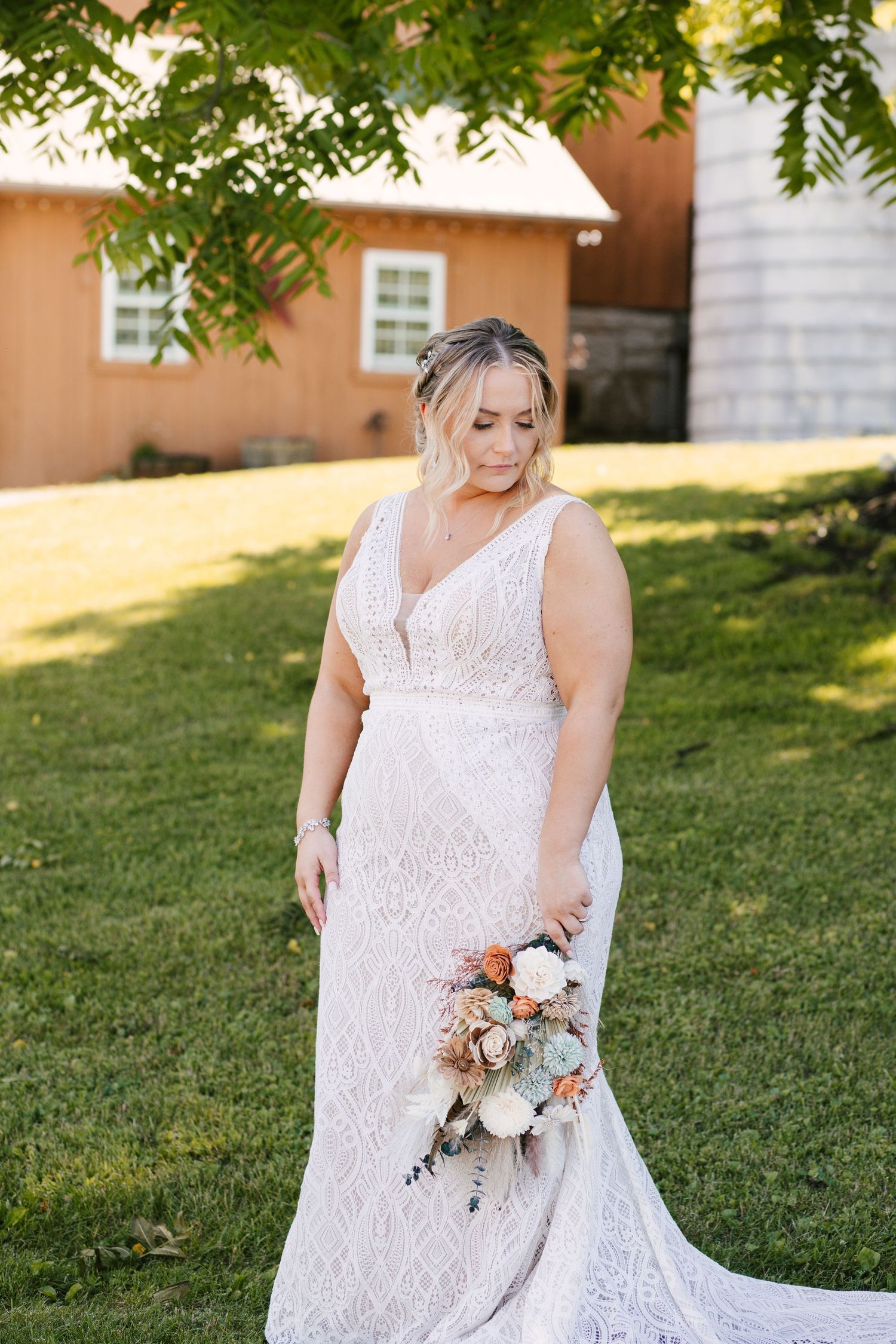 Elegant lace wedding dress details shown in a garden setting with soft natural lighting.