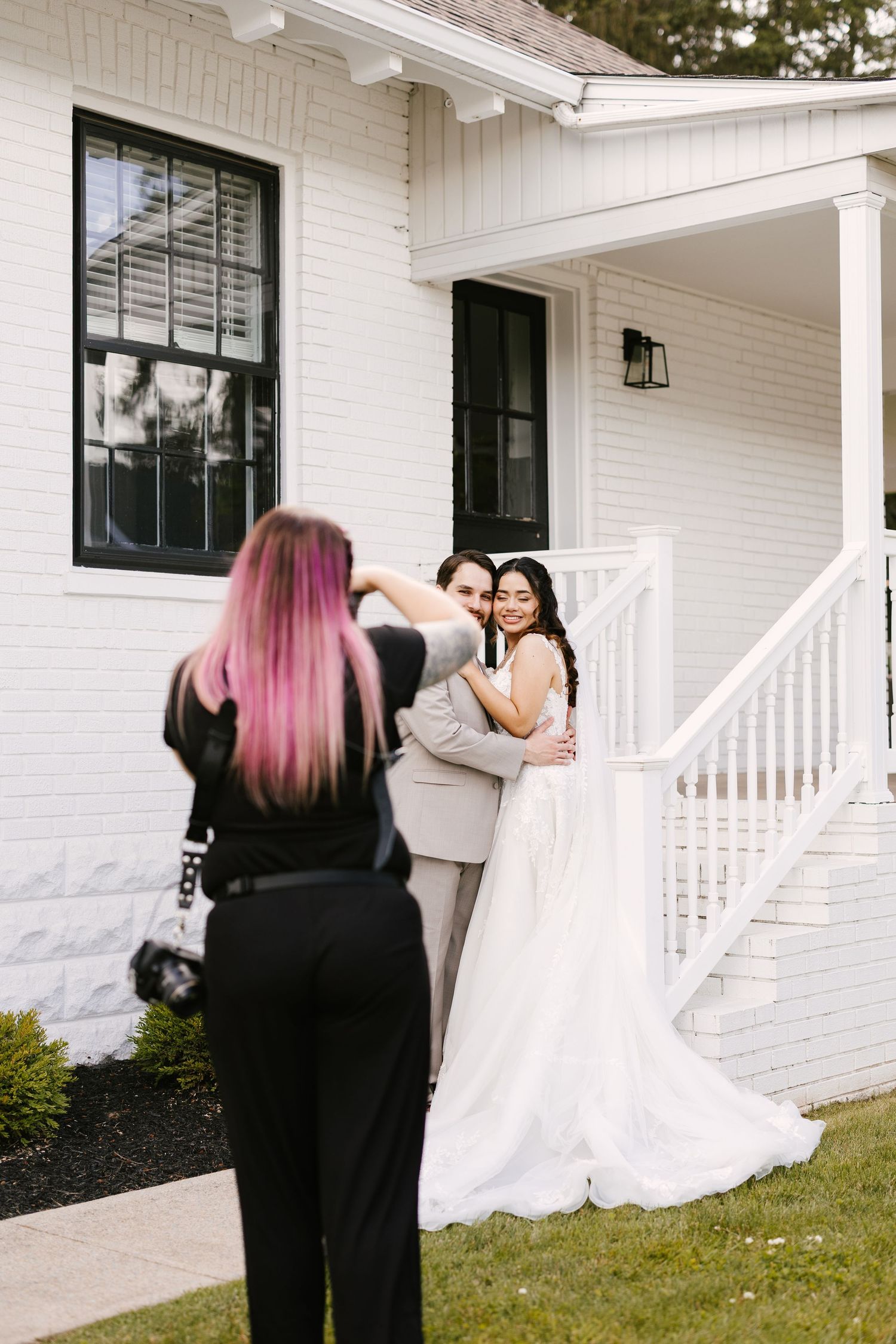 Behind-the-scenes shot of photographer capturing wedding portraits on white porch.