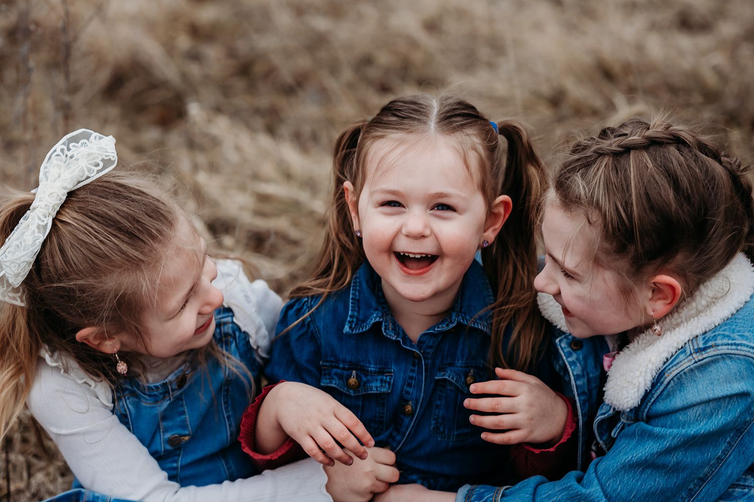 Joyful children in denim jackets laughing and playing together outdoors during an overcast family photo session in Avon, Indiana.