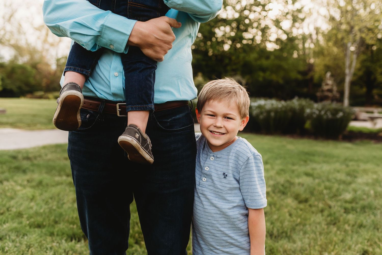 A sweet boy hugs dad during golden hour, wearing coordinating blue outfits.