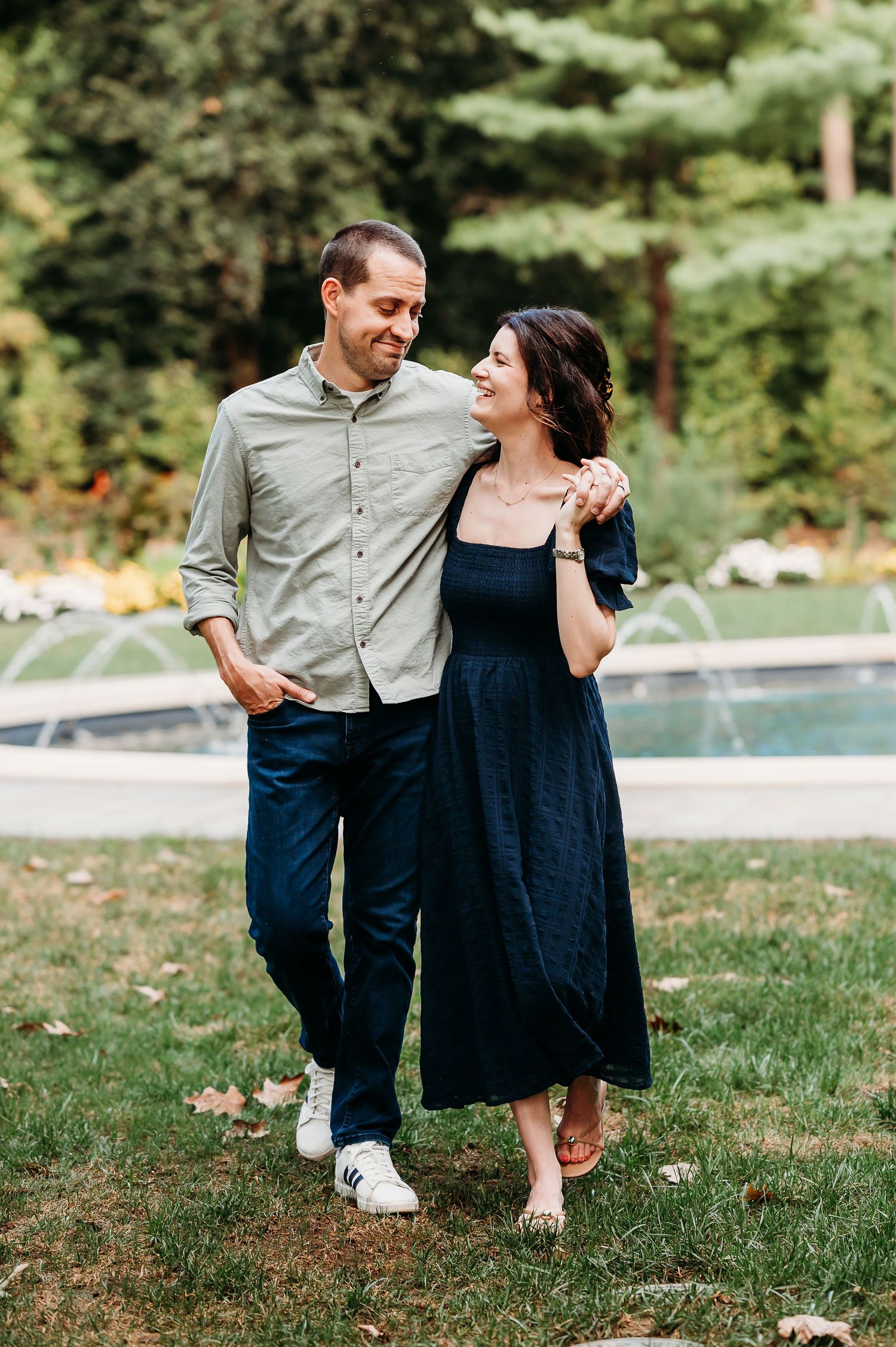 A couple shares playful moments together on Newfield's grassy lawn by the fountain during an Indianapolis summer photo session.