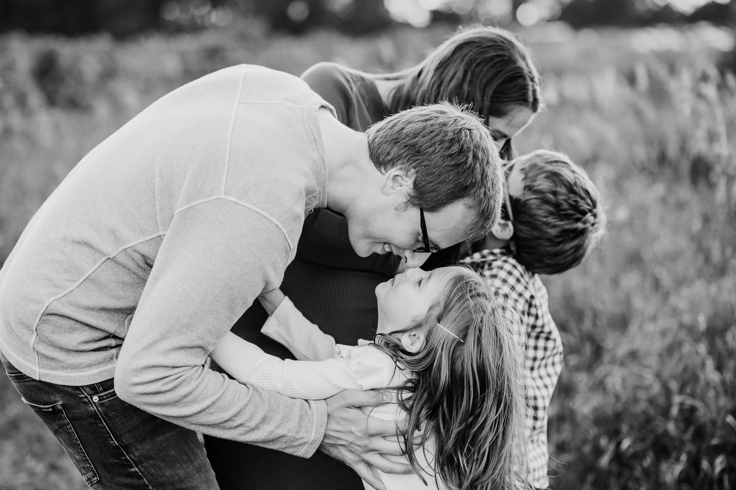 Black and white photo capturing tender moments between parents and children sharing laughter outdoors at Prophetstown State Park in Indiana.