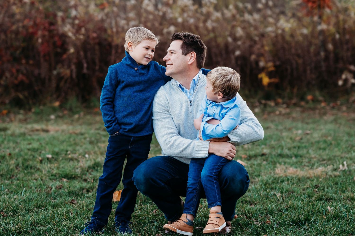Family enjoying a playful moment together outdoors during an autumn photo session in a natural setting in Fishers, Indiana.