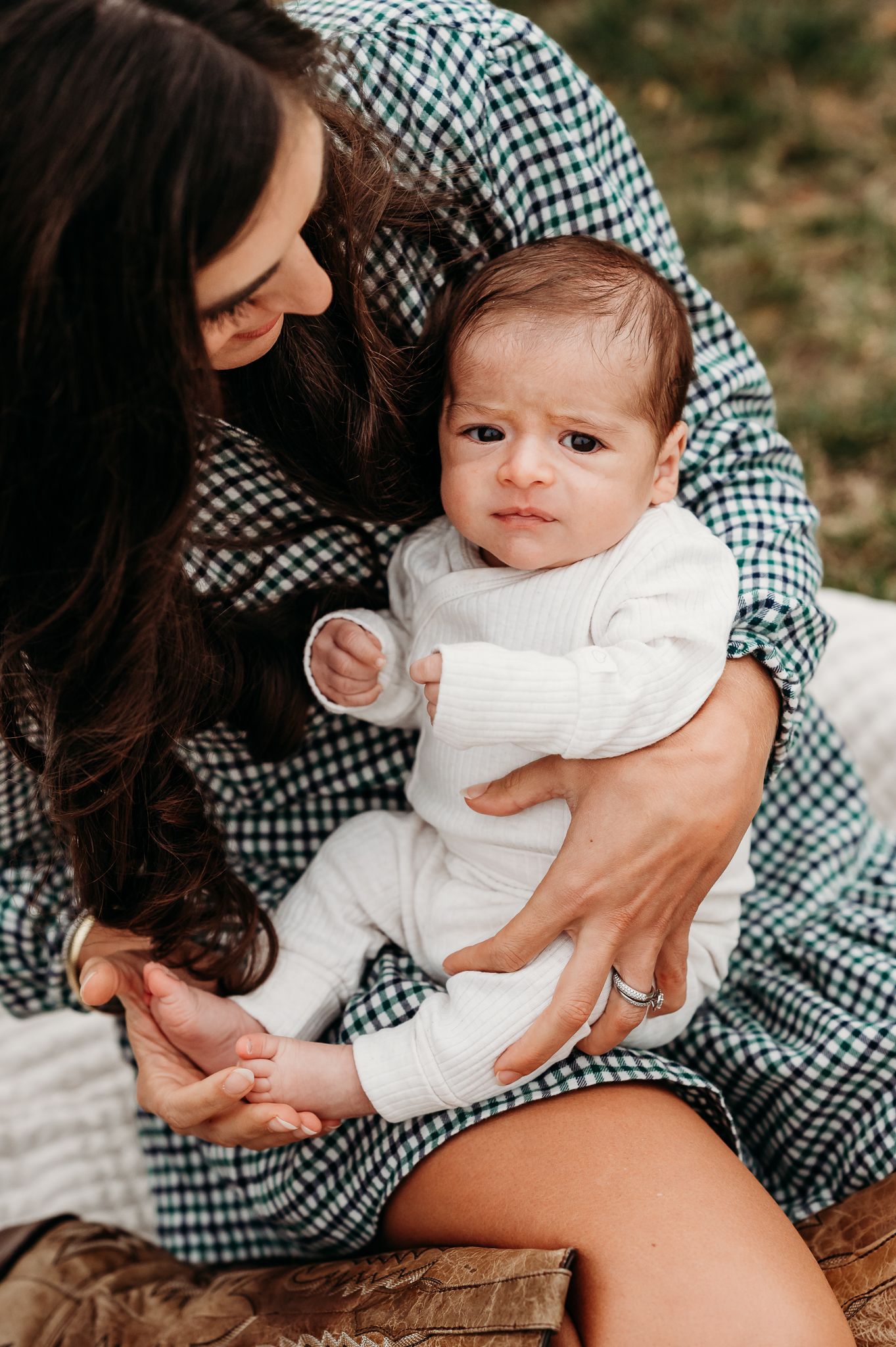 A tender moment captured between mom in a gingham dress and baby boy during fall outdoor newborn photos in Avon, Indiana.