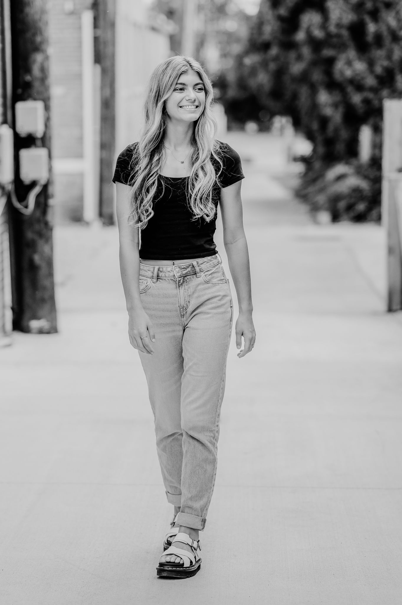 Black and white portrait shot of a young person walking outdoors in casual attire of jeans and t-shirt.
