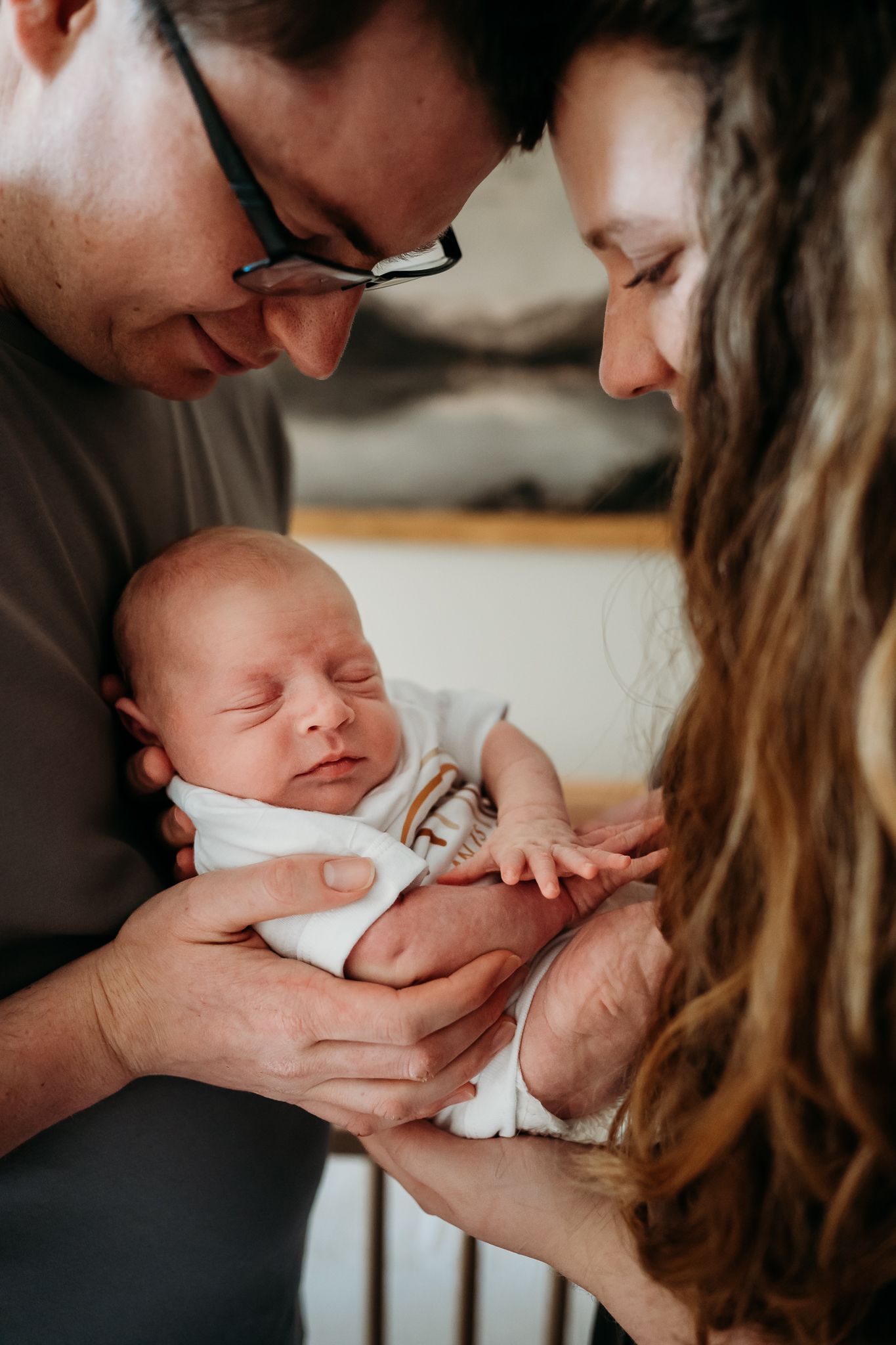 Parents lovingly cradle and admire their sleeping newborn baby in intimate close-up shot in their Greenwood, Indiana, nursery.
