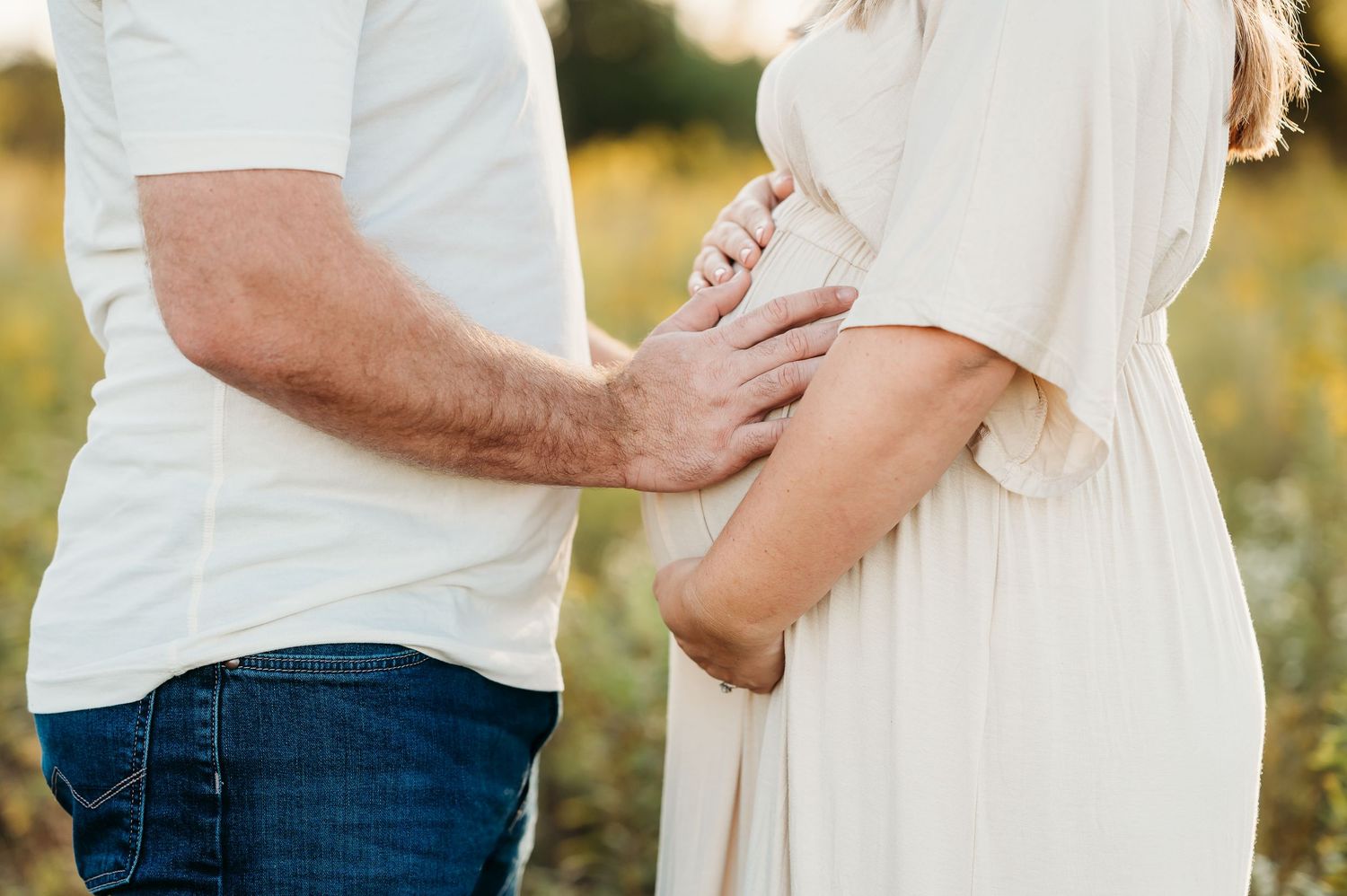 An expecting Indianapolis couple puts hands on baby during a golden hour outdoor maternity photo session.