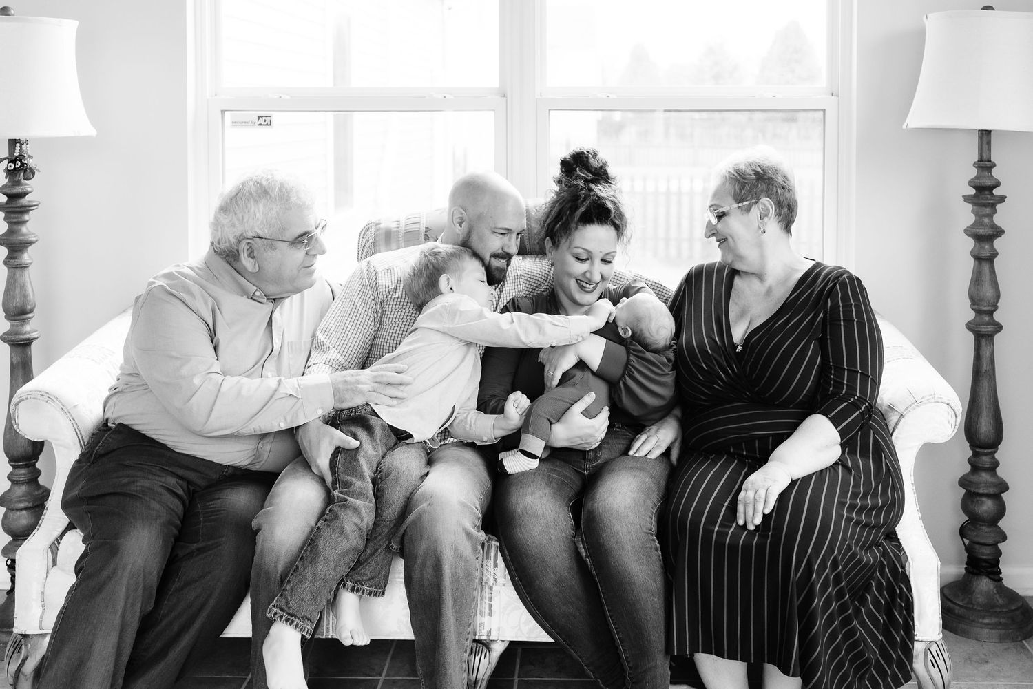 Black and white photo capturing family photo with grandparents and baby boy during newborn photos at Avon, Indiana, home.