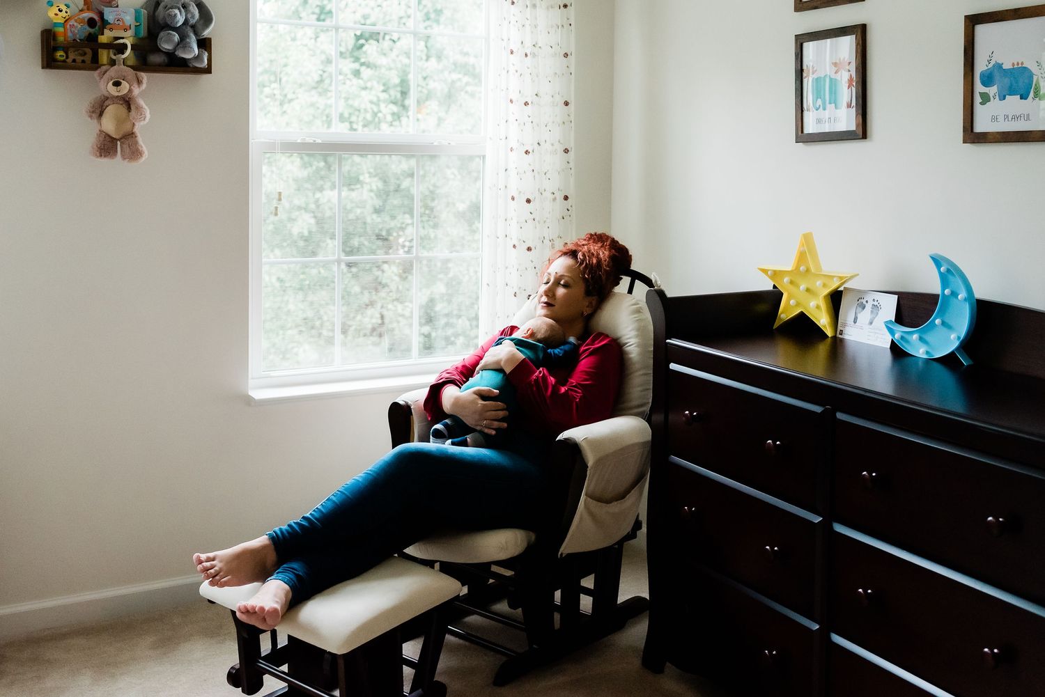 A child practices piano while lying down on a bench in a bright room with colorful decorations on the wall.