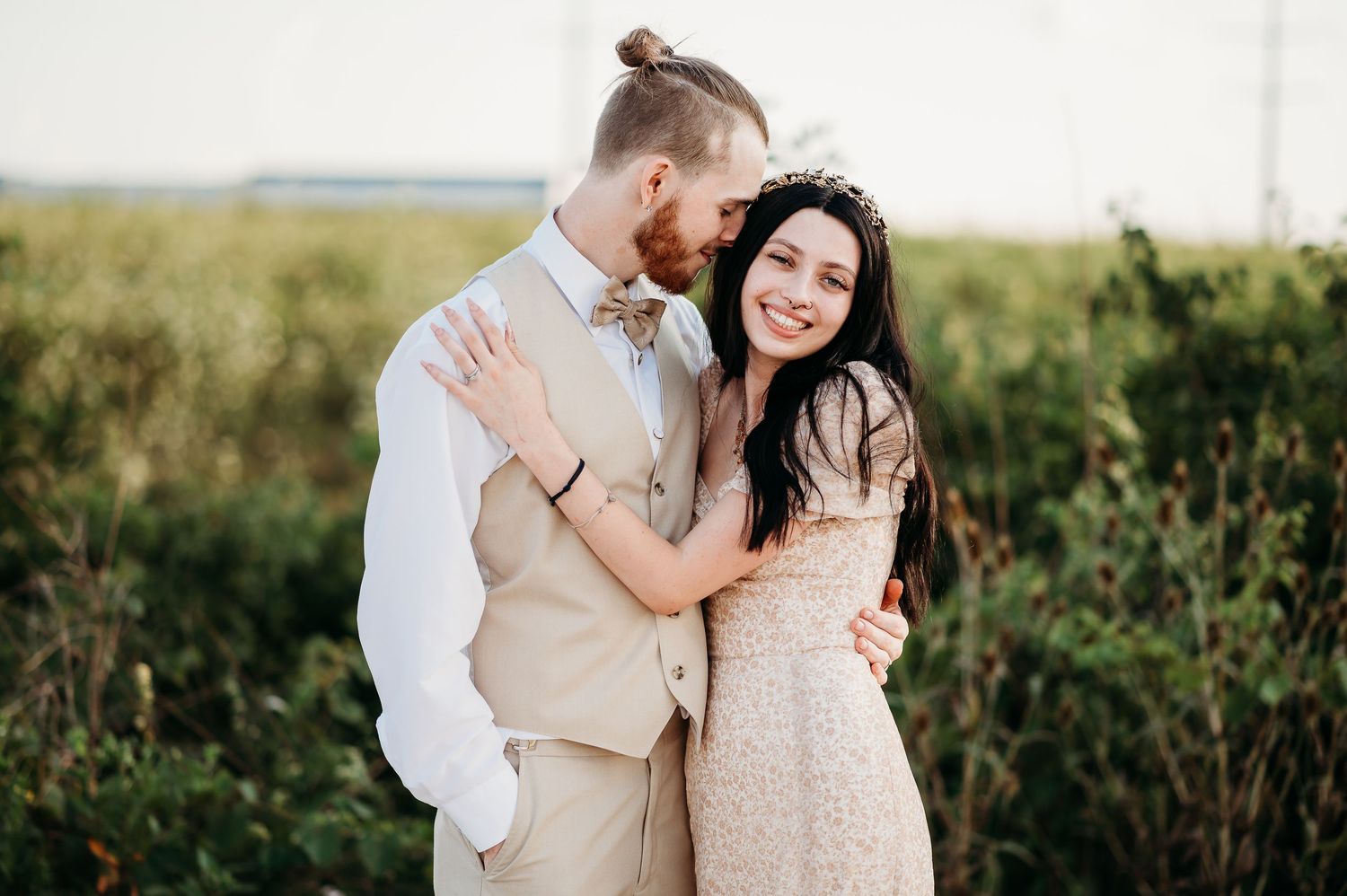 A romantic outdoor photoshoot in a sunlit field with natural greenery in the background.