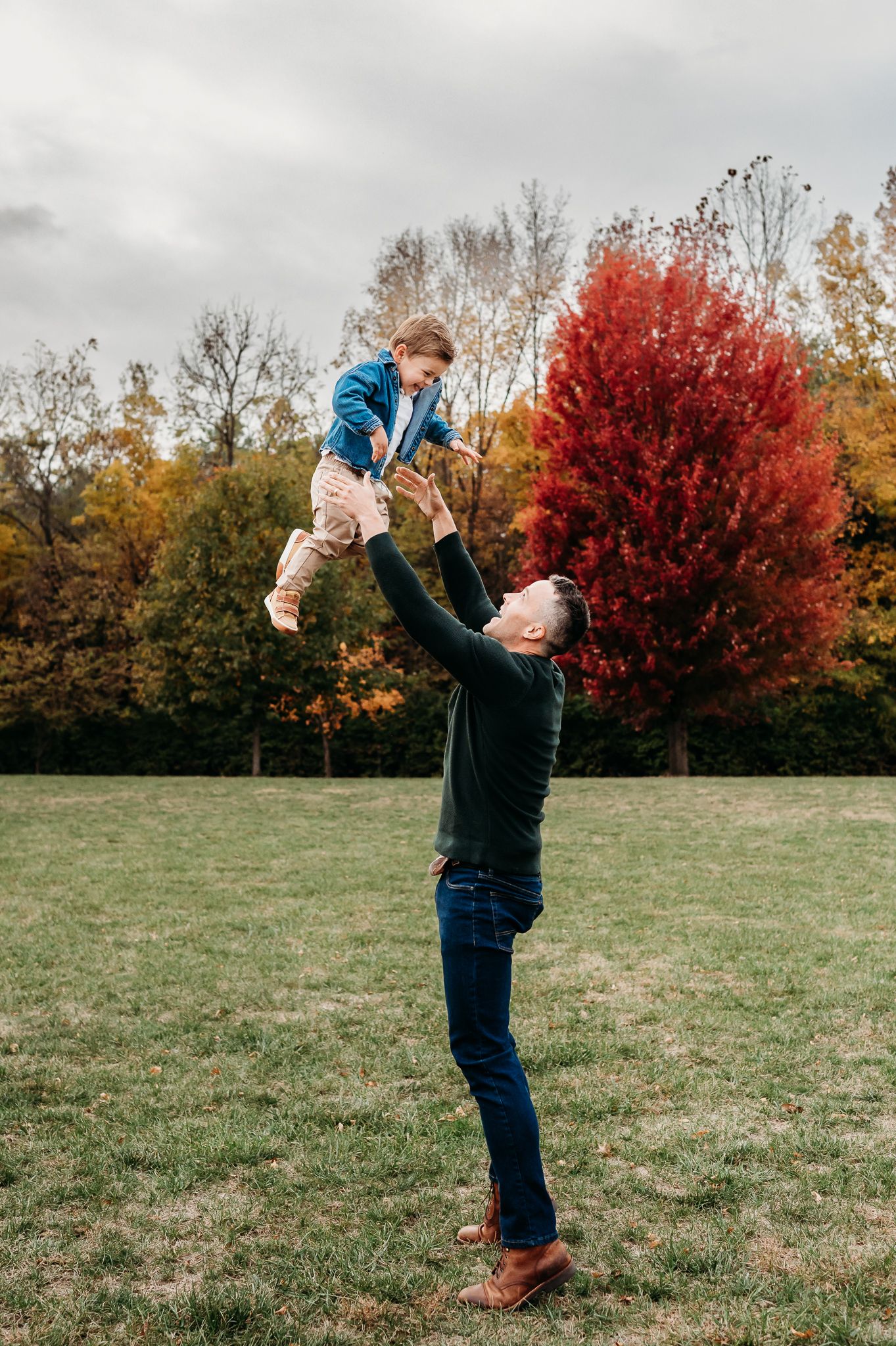 A joyful autumn scene in an Avon, Indiana, park with vibrant red maple tree and golden foliage in the background during fall family photos.
