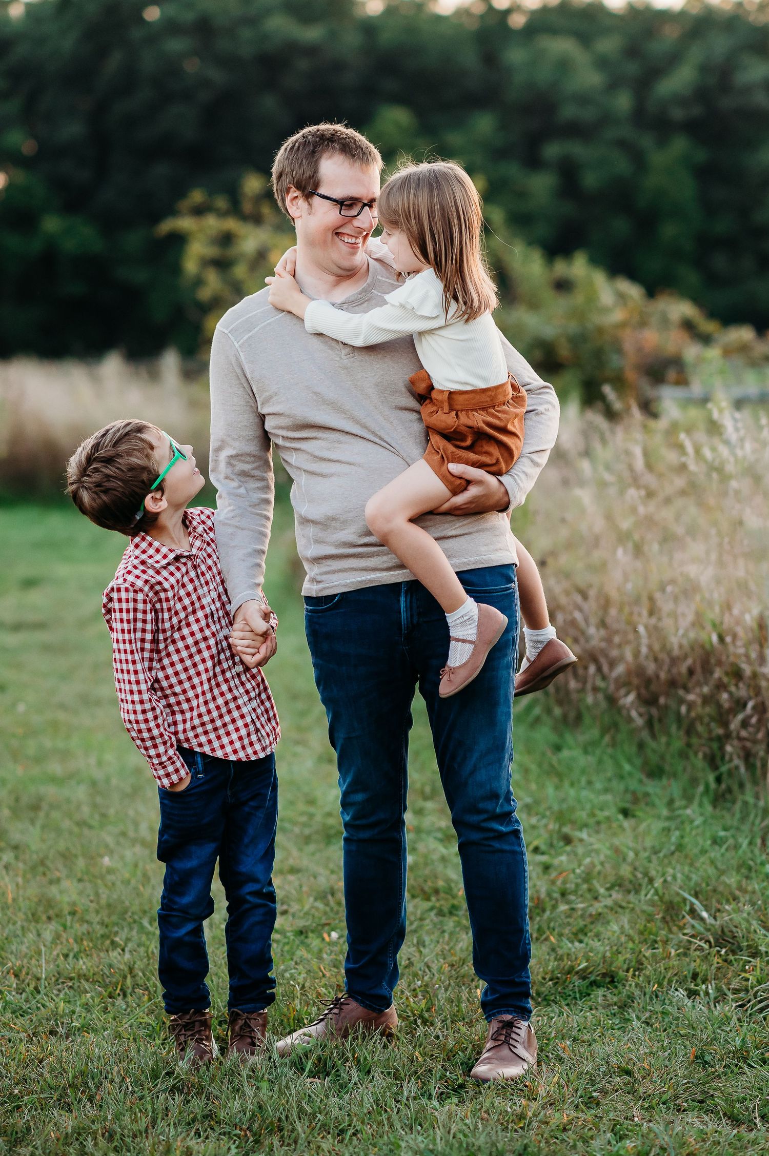 A family enjoying a tender moment together outdoors in a grassy field at sunset at Prophetstown State Park in West Lafayette, Indiana.