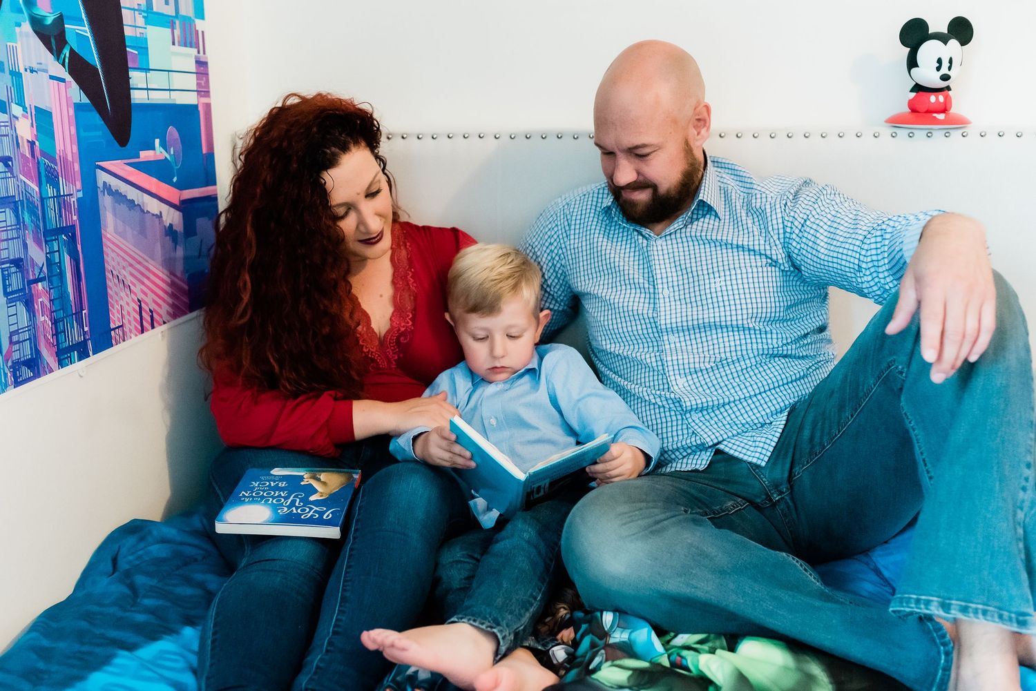 Family reading together in a bright boy's room with Disney decor and toys during lifestyle photo session in Avon with Sara House Photography