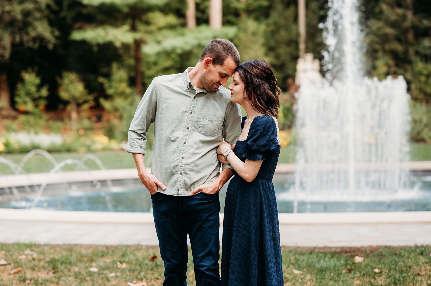 A romantic couple shares an intimate moment together in front of a beautiful fountain in a garden setting at Newfields in Indianapolis.