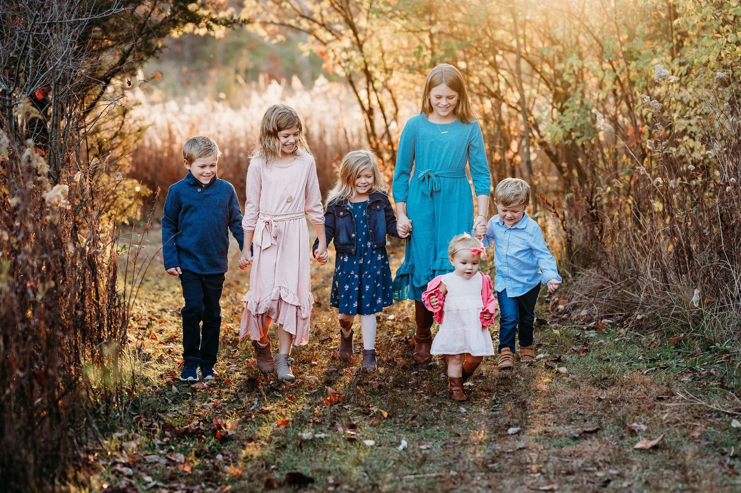 Children walk together along a nature trail during sunset with golden light streaming through the branches at Ritchey Woods in Fishers, IN.
