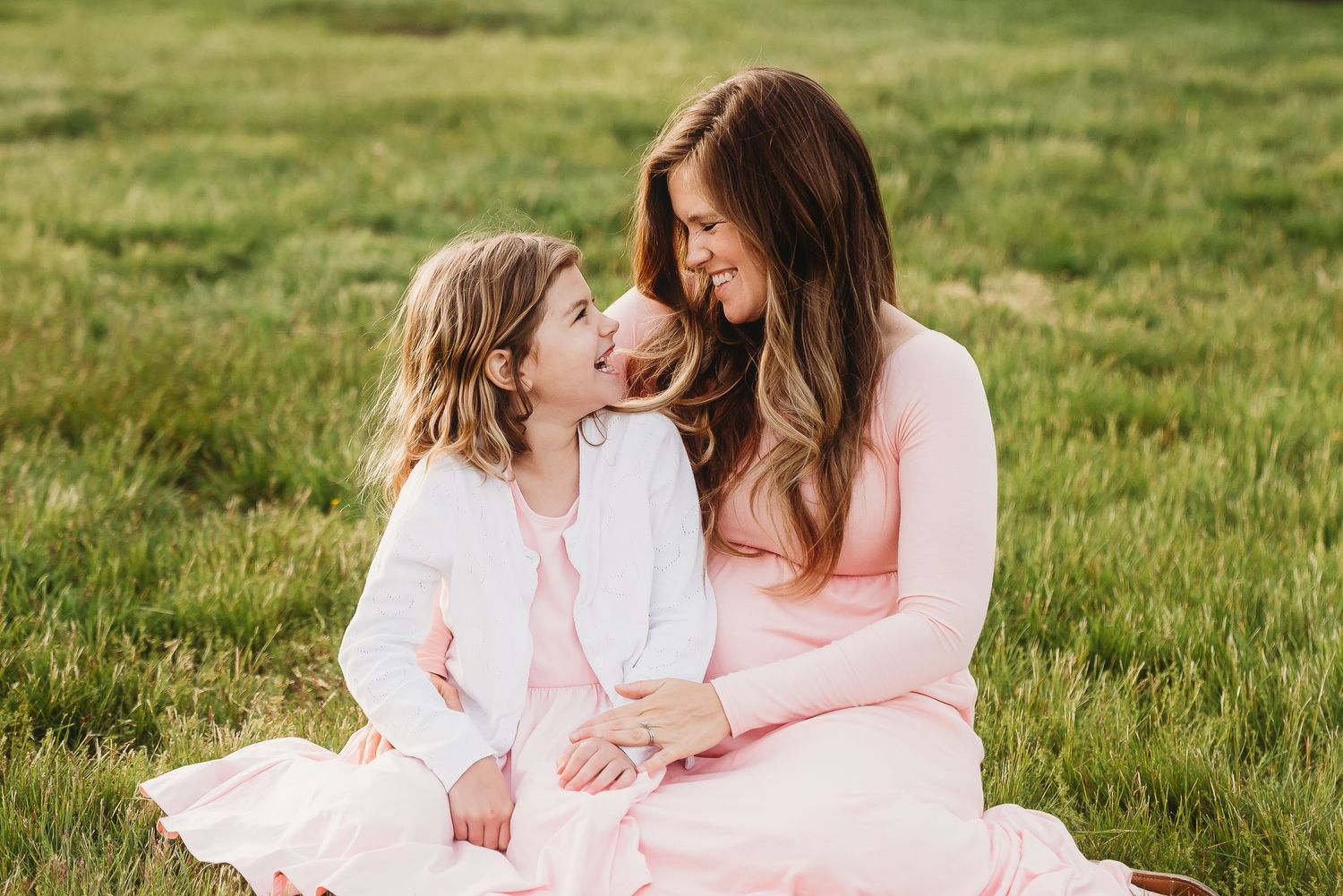 Mom and daughter portrait captured in a serene outdoor setting with soft pink and white clothing.