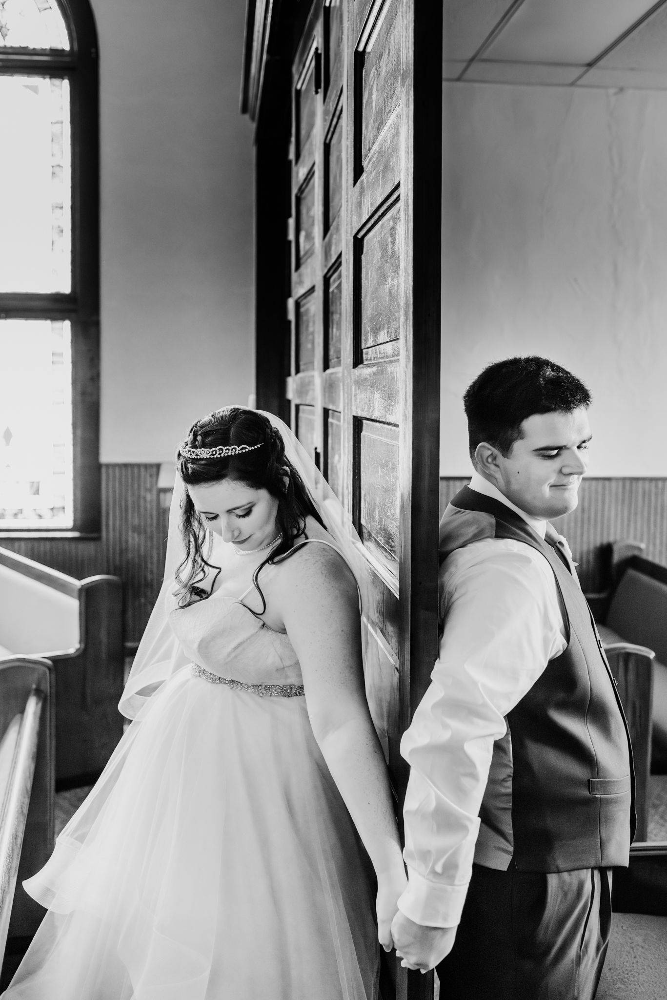 A black and white photo series showing a couple getting ready for their wedding in a room with framed artwork.