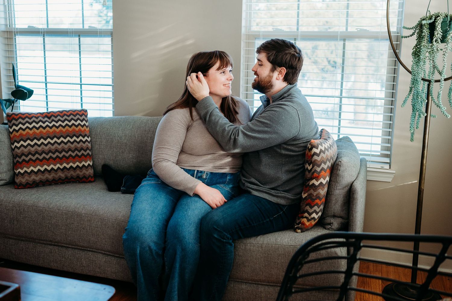 An Indianapolis couple shares an intimate moment on a gray couch, with the man gently touching the womans face.